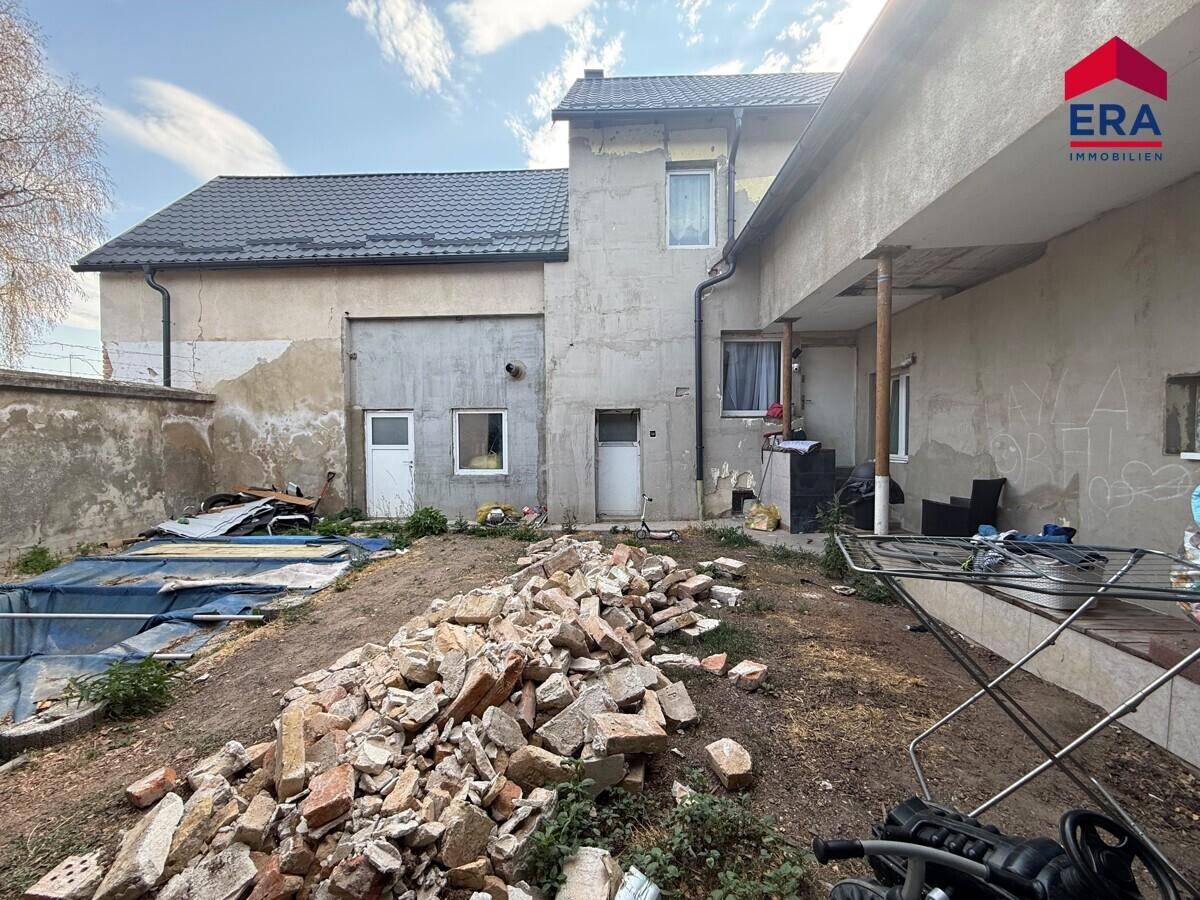 Rückansicht des Gebäudes mit unaufgeräumtem Hinterhof und Bauschutt.