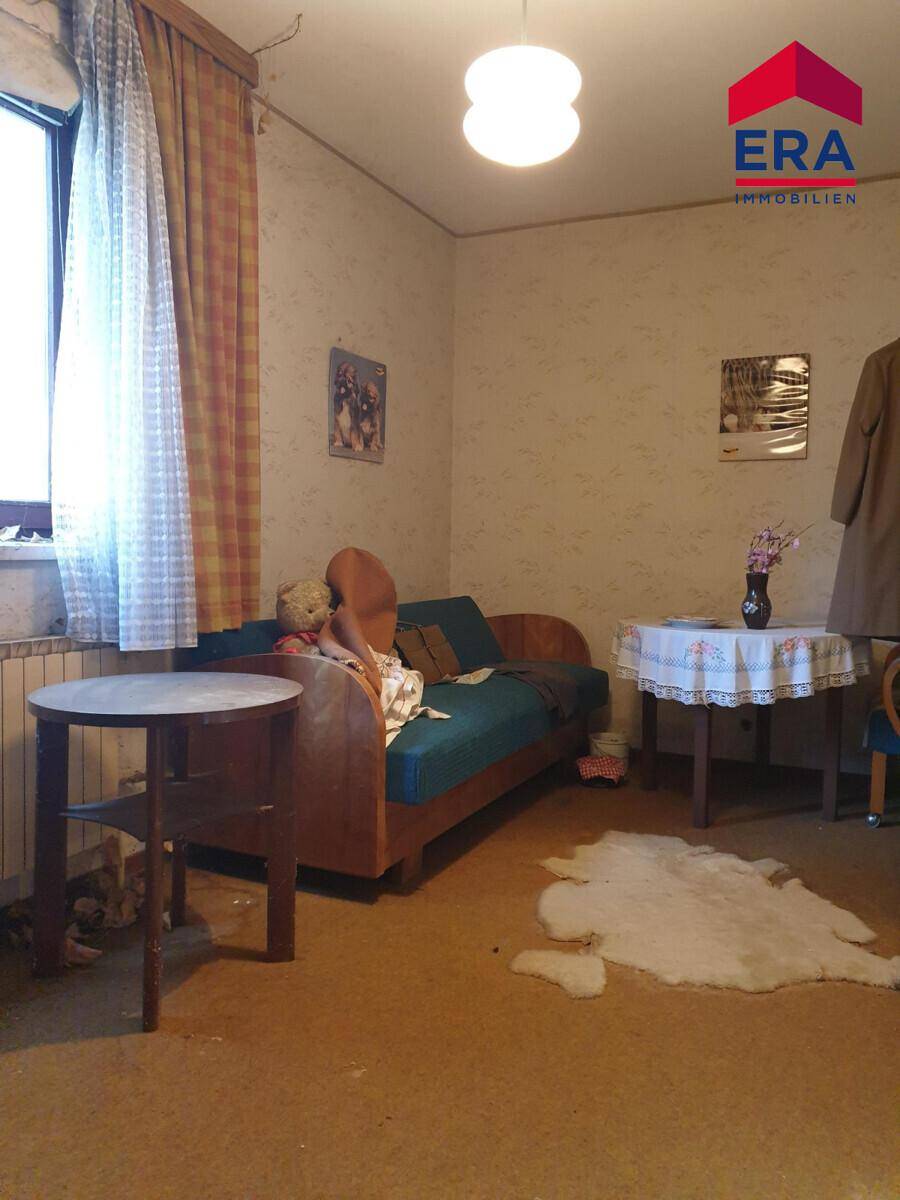 Schlafzimmer mit Einzelbett, gemusterter Tapete und einem Fenster für natürliches Licht.