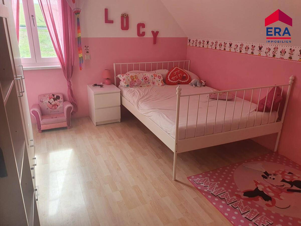 Kinderzimmer mit rosa Wänden, Laminatboden und Fenster mit Blick ins Grüne.