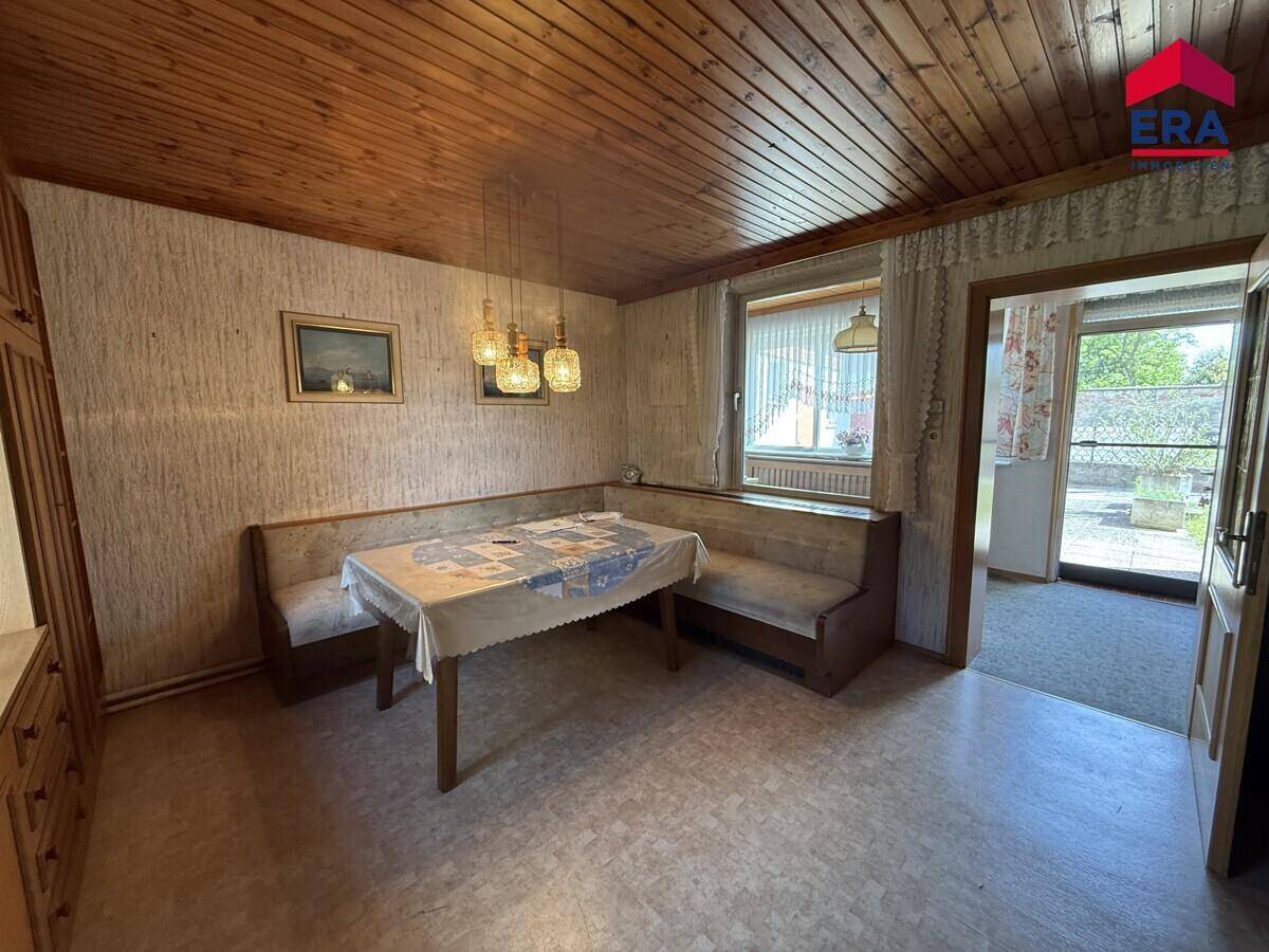 Essbereich mit eingebauter Sitzbank, Holztisch und einer Holzpaneeldecke.