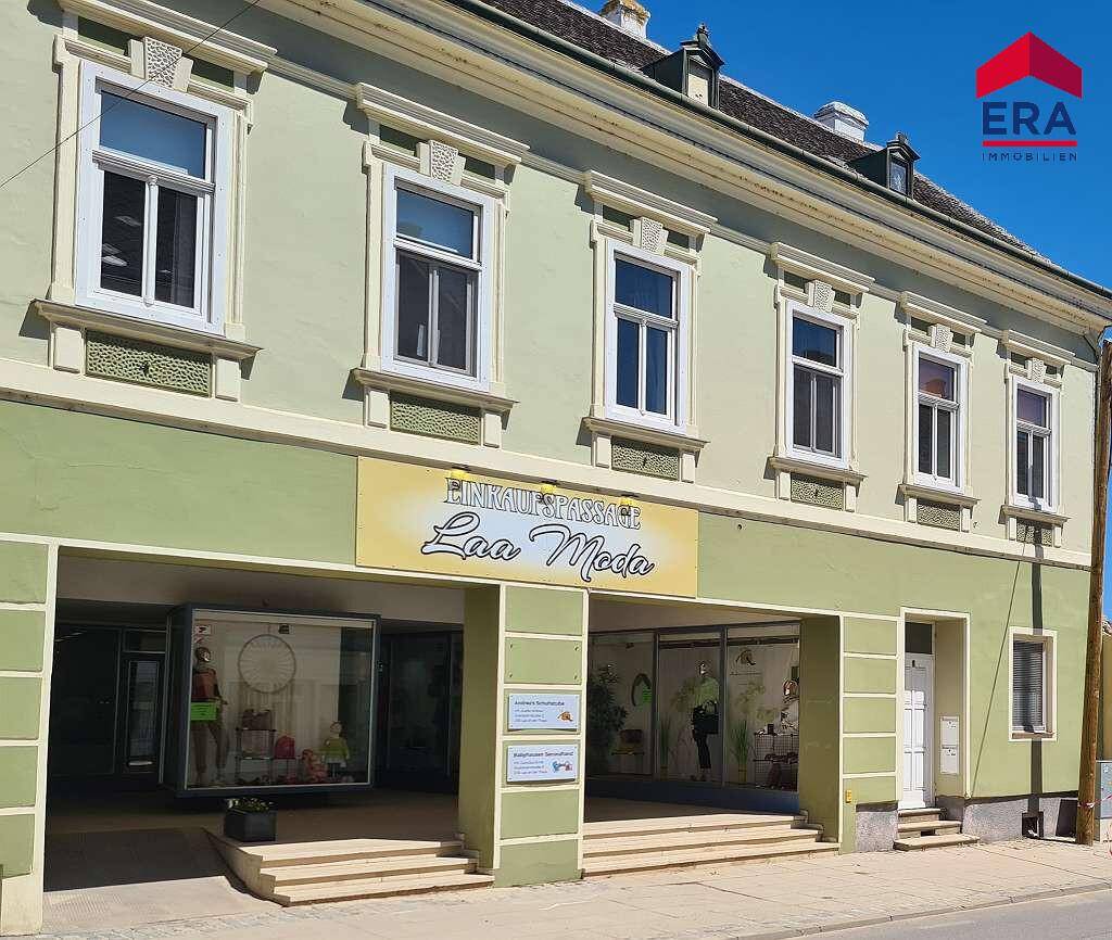 Historische Fassade eines Gebäudes mit Geschäften im Erdgeschoss und Wohnungen darüber.