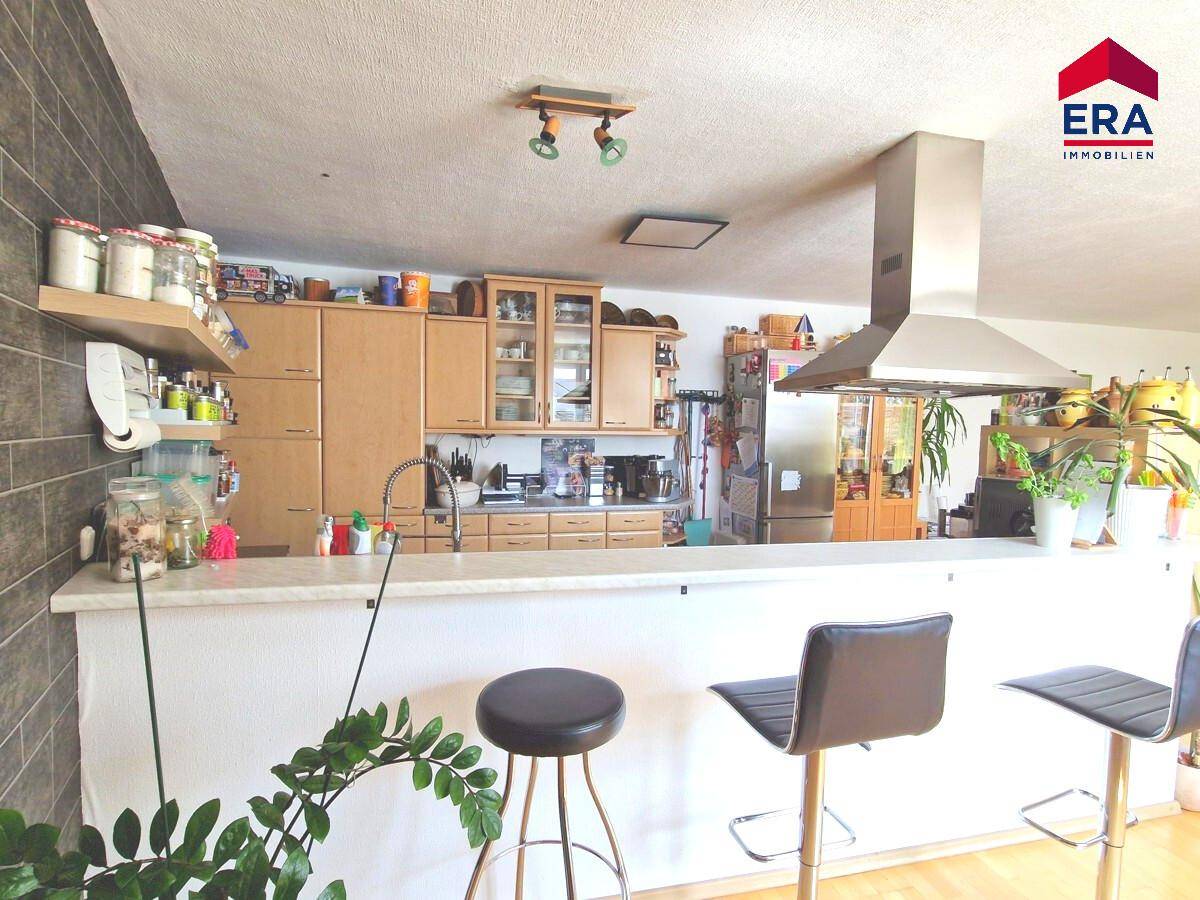 Offene Küche mit Bar, Holzschränken und Edelstahlgeräten, ideal für geselliges Kochen.