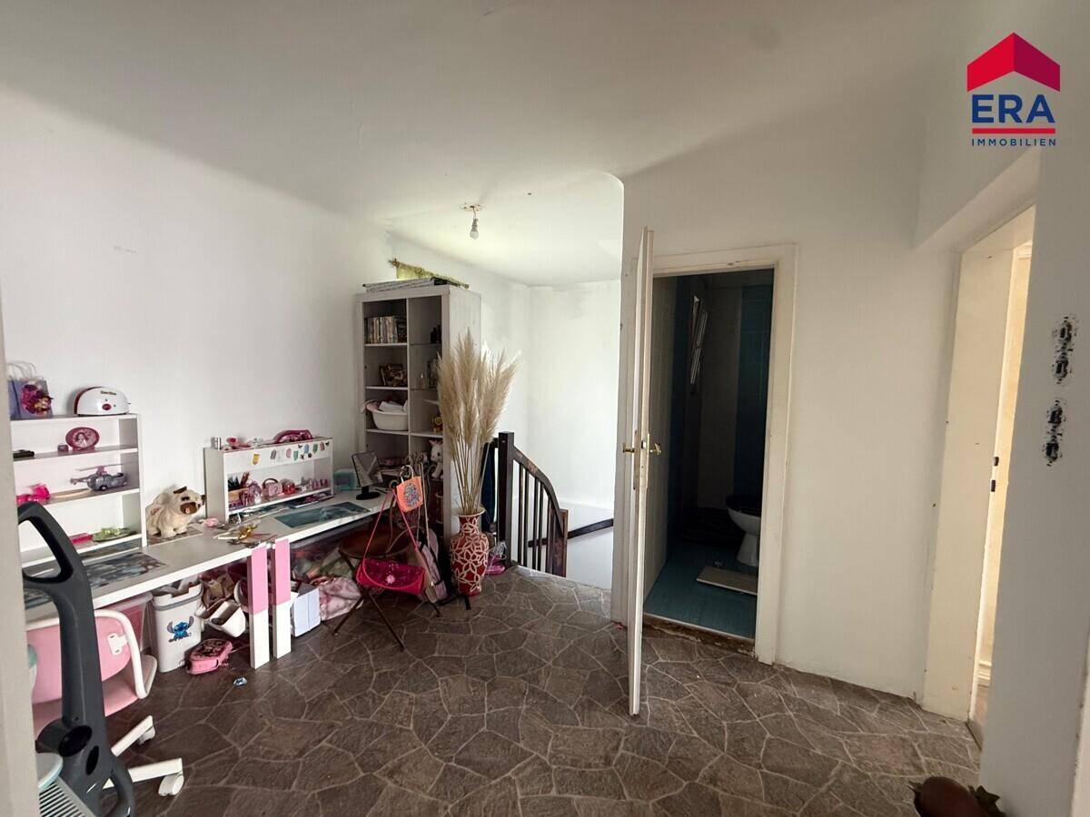 Geräumiger Flur im Obergeschoss mit Schreibtisch, Bücherregal und Treppenabgang.