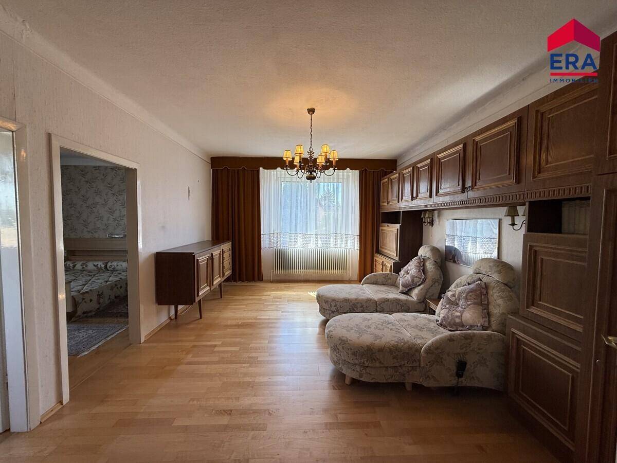 Geräumiges Wohnzimmer mit Holzfußboden, Einbauschränken und einem großen Fenster.