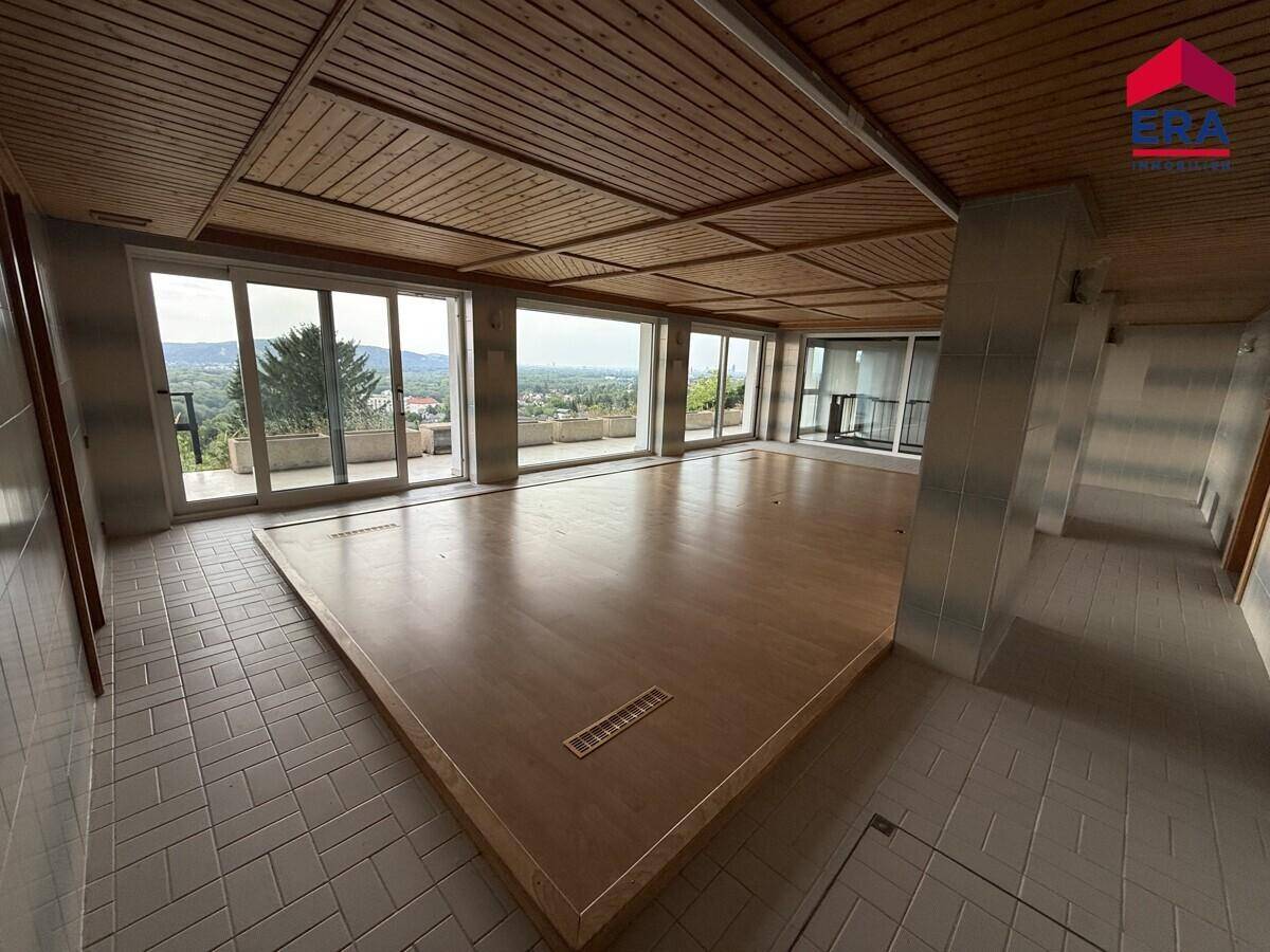 Großer Wohnraum mit Holzbalkendecke, Panoramafenstern und weitem Ausblick über die Landschaft.