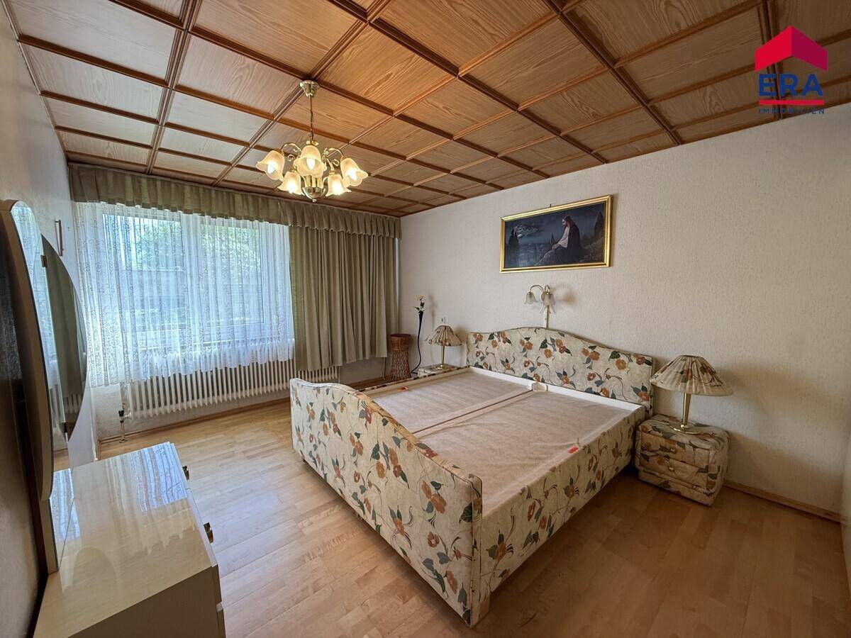Schlafzimmer mit Holzfußboden, Doppelbett und einer Decke mit Holzpaneelen.
