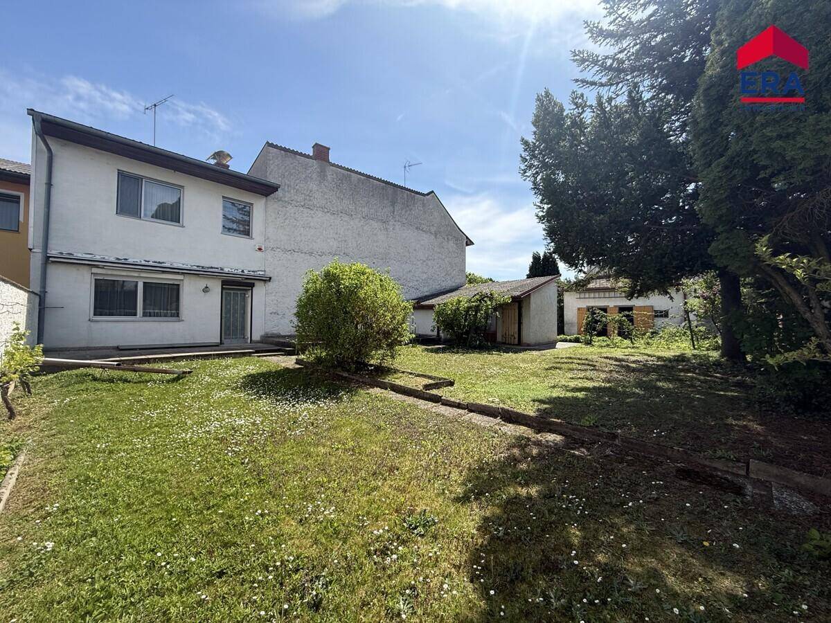 Hinteransicht des Hauses mit einem weitläufigen, grünen Gartenbereich und Bäumen.