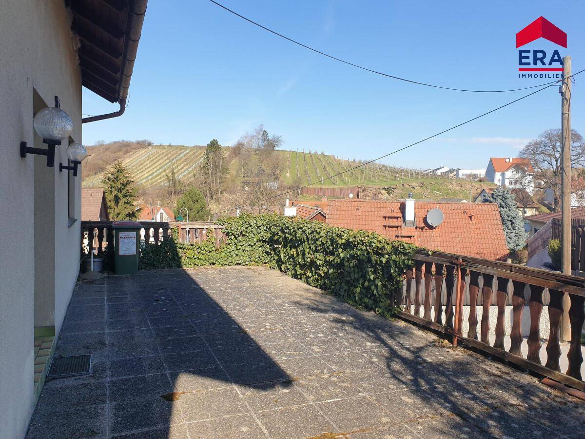 Große Außenterrasse mit Holzzaun, Efeu und weitem Blick auf die Weinberge und Umgebung.