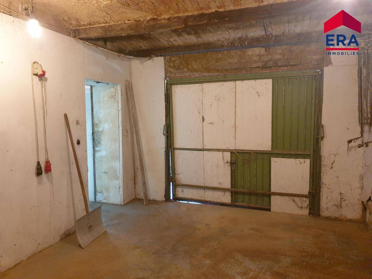 Geräumige Garage im Kellergeschoss mit großem Tor und Zugang zu weiteren Räumen.