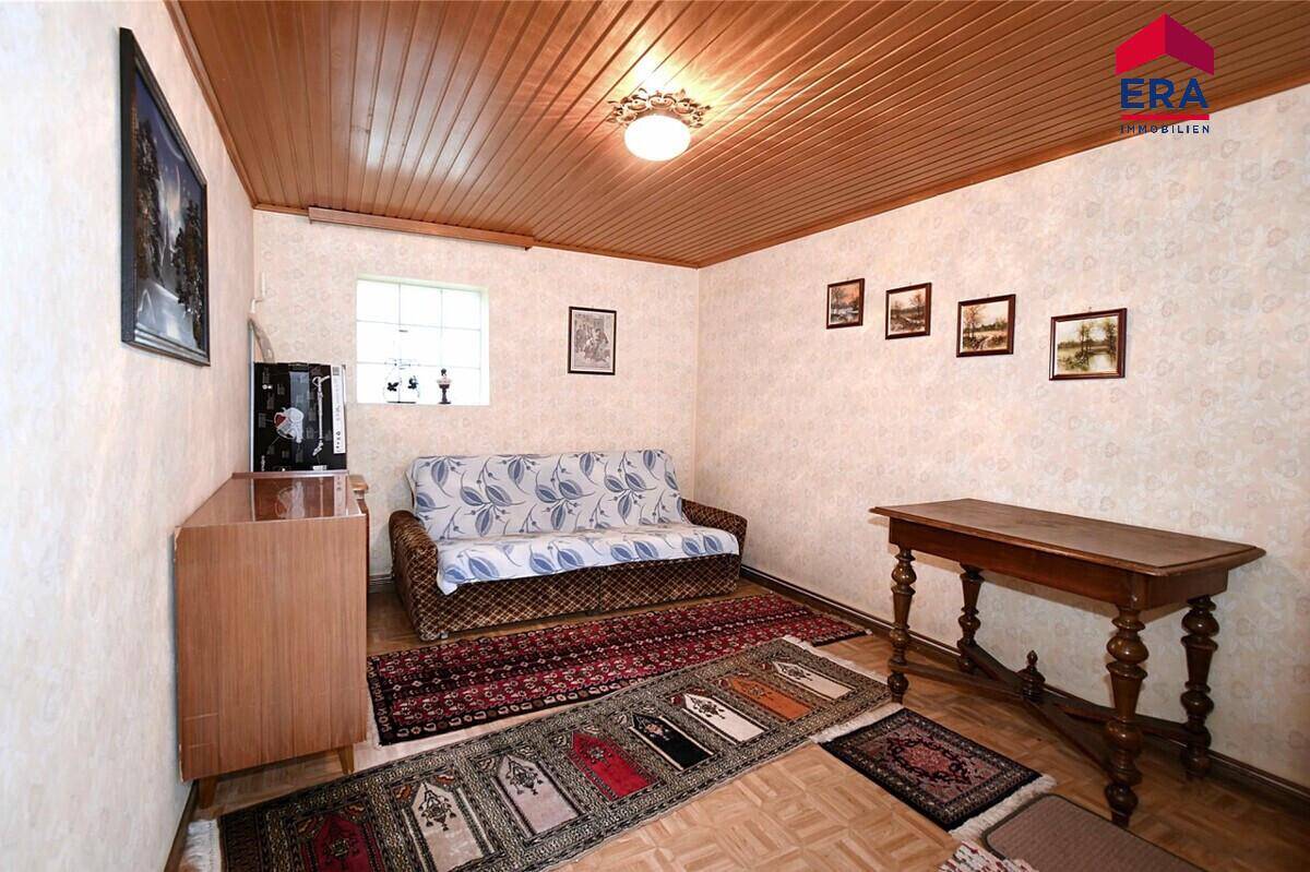Gemütliches Zimmer mit Sofa, Holztisch und Teppichen.