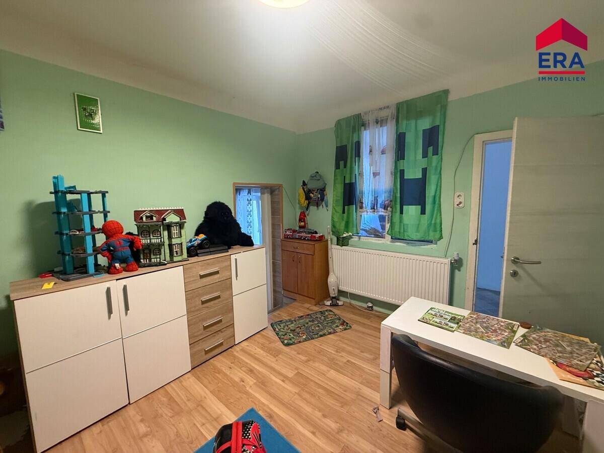 Freundliches Kinderzimmer mit grünen Wänden, Schreibtisch und Fenster.