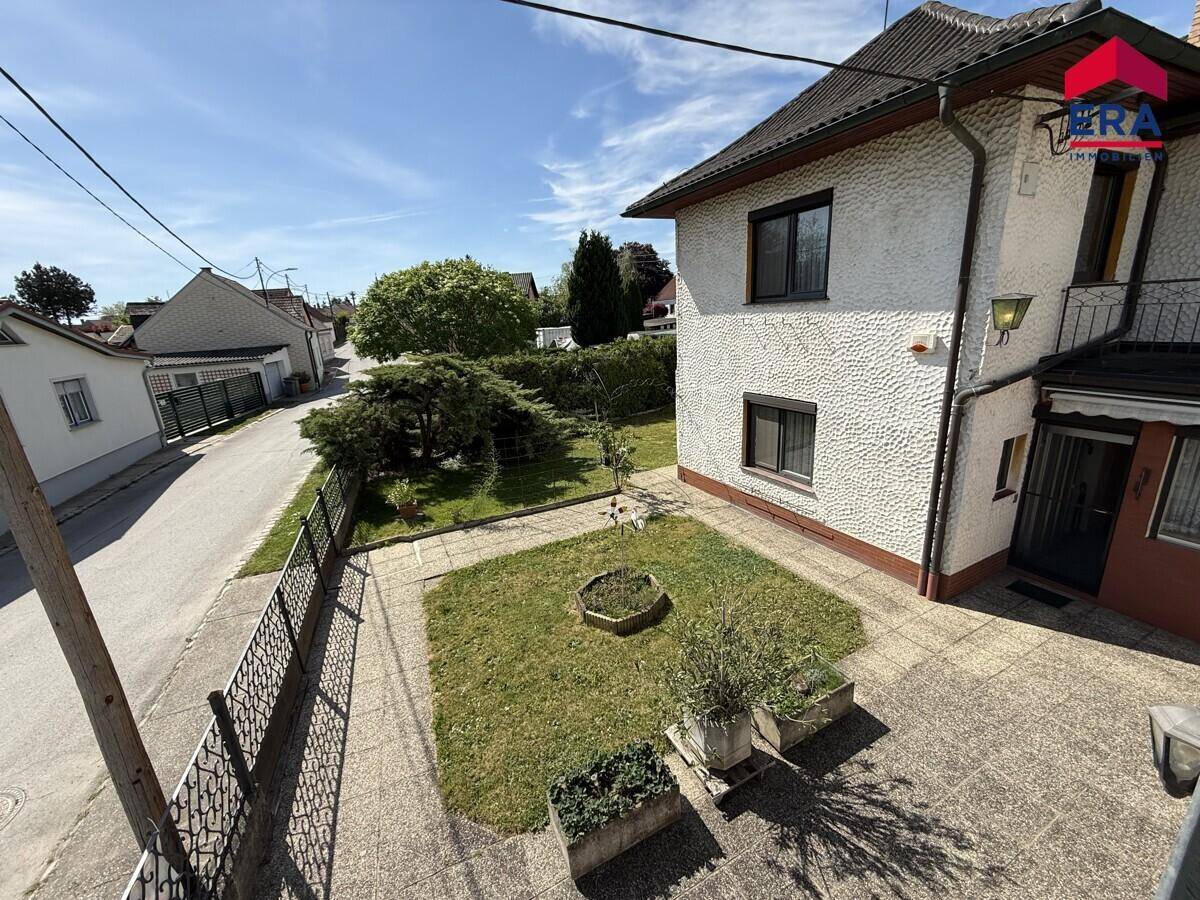 Erhöhte Ansicht des Vorgartens und der Straße mit dem Haus im Hintergrund.