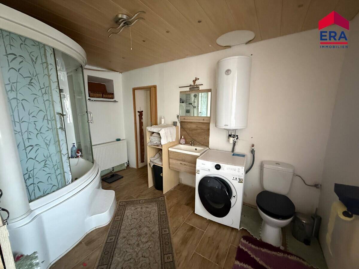 Badezimmer mit Duschkabine, Waschbecken, Toilette und Waschmaschine.