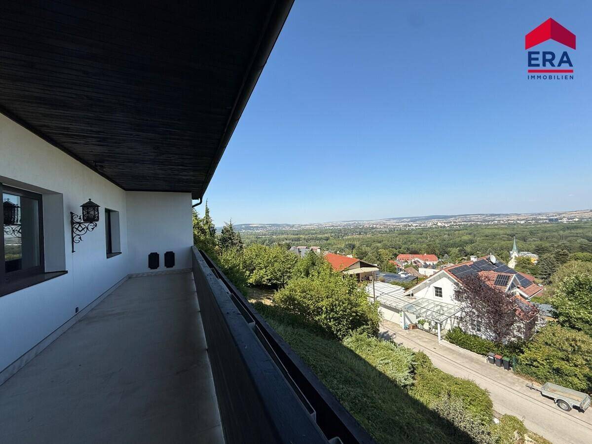 Langer Balkon entlang der Hausseite mit weitem Blick über die grüne Landschaft.