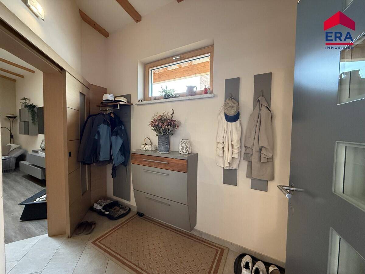 Heller Eingangsbereich mit Garderobe, Schuhschrank und Holzbalken an der Decke.