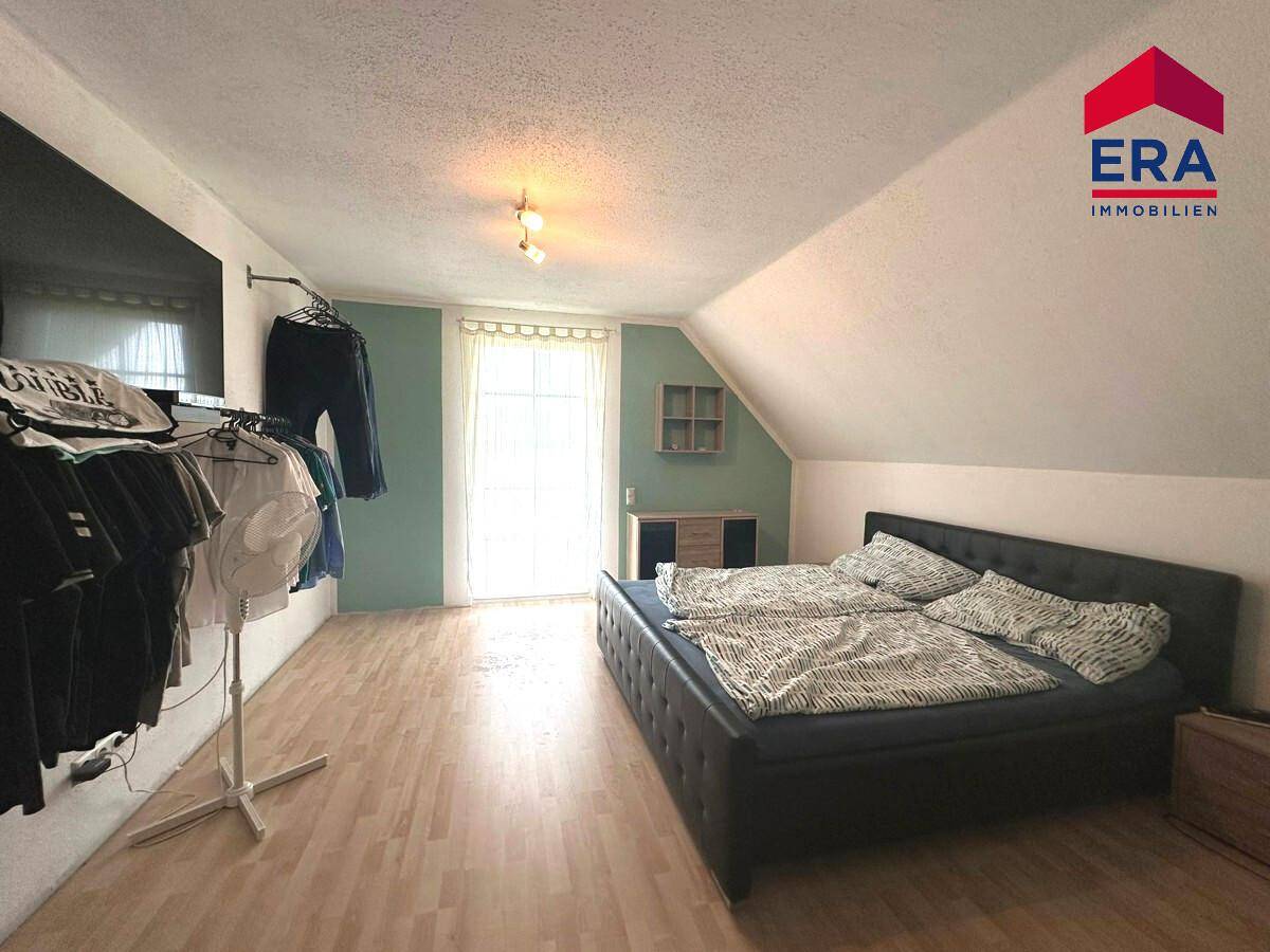 Gemütliches Schlafzimmer im Dachgeschoss mit Holzboden und Kleiderstange.