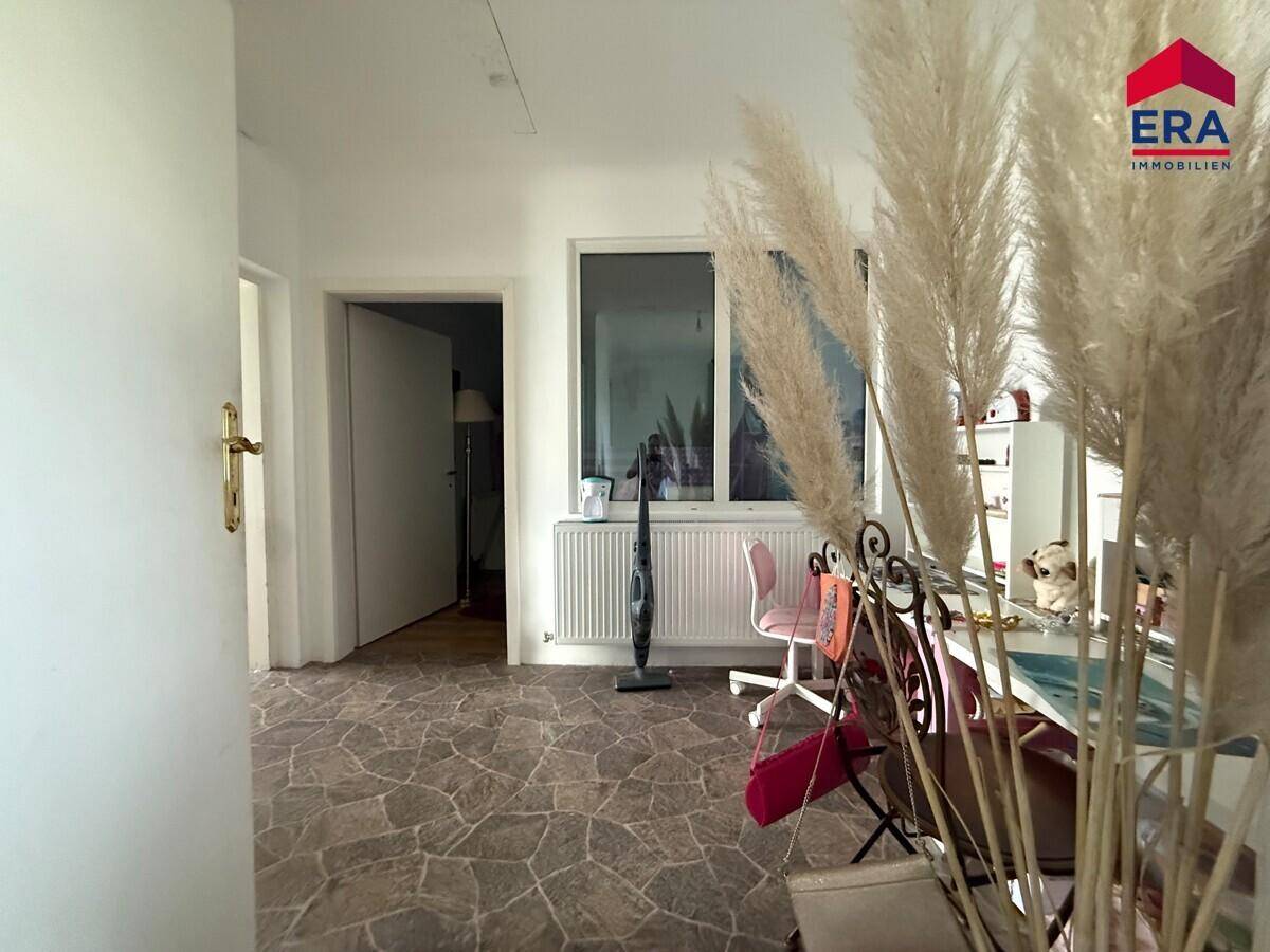 Heller Flurbereich im Obergeschoss mit Fenster und dekorativen Pflanzen.