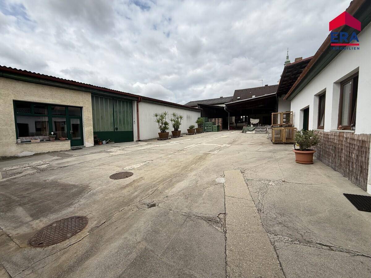 Großer gepflasterter Innenhof mit mehreren Gebäuden und Pflanzenkübeln.