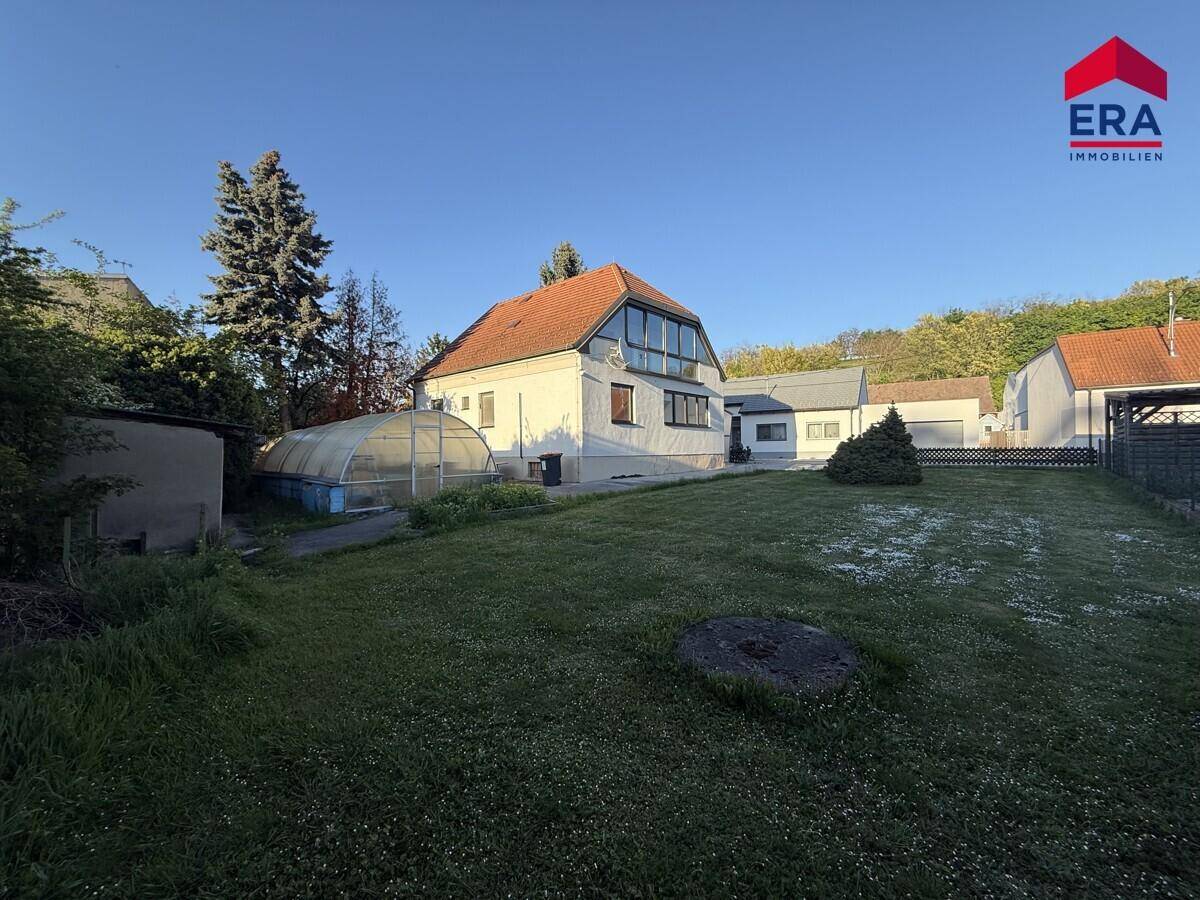 Großer Garten hinter dem Haus mit Rasenfläche, Bäumen und einem überdachten Pool.