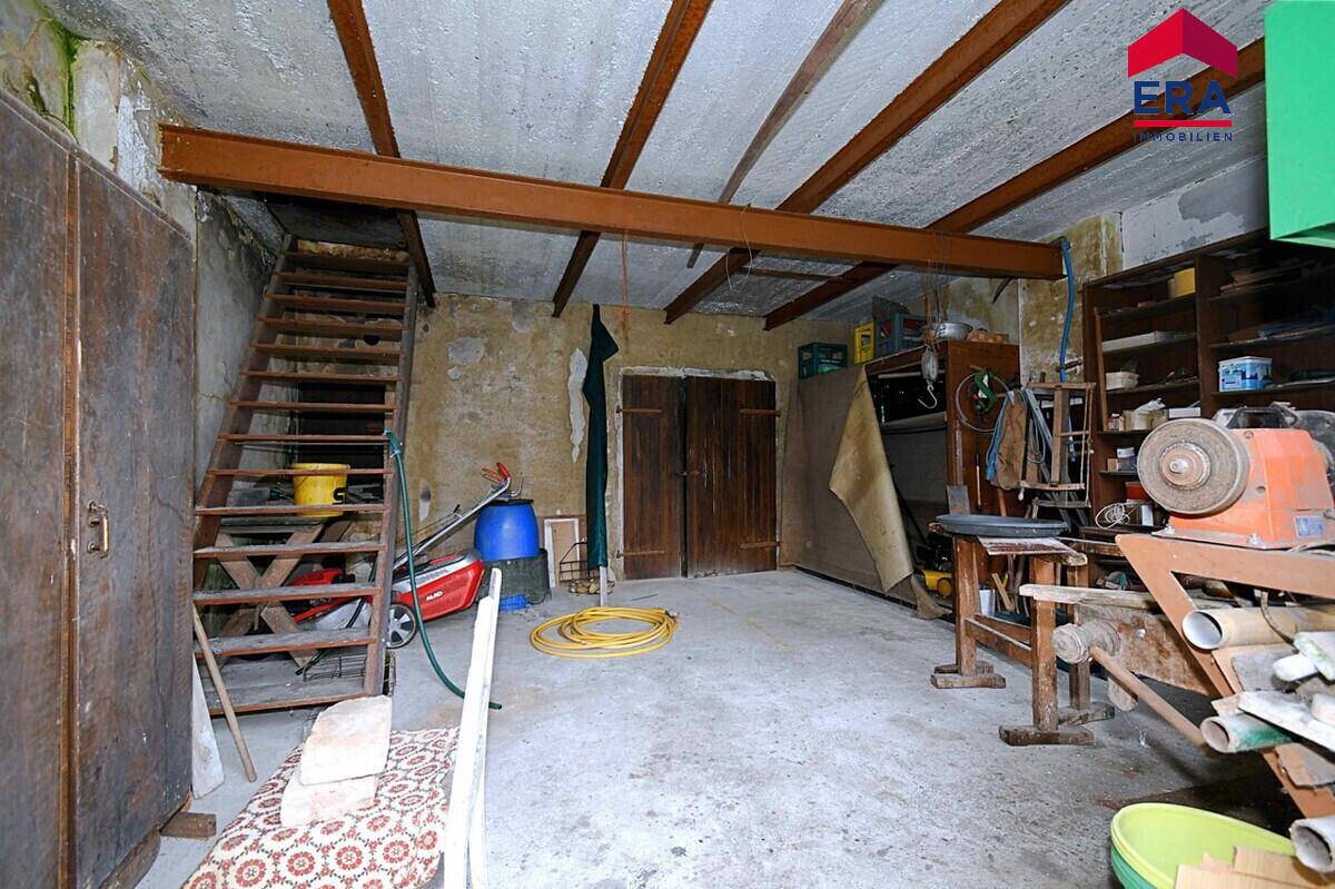 Unausgebauter Kellerraum mit Holztreppe, Betonboden und Lagerflächen.