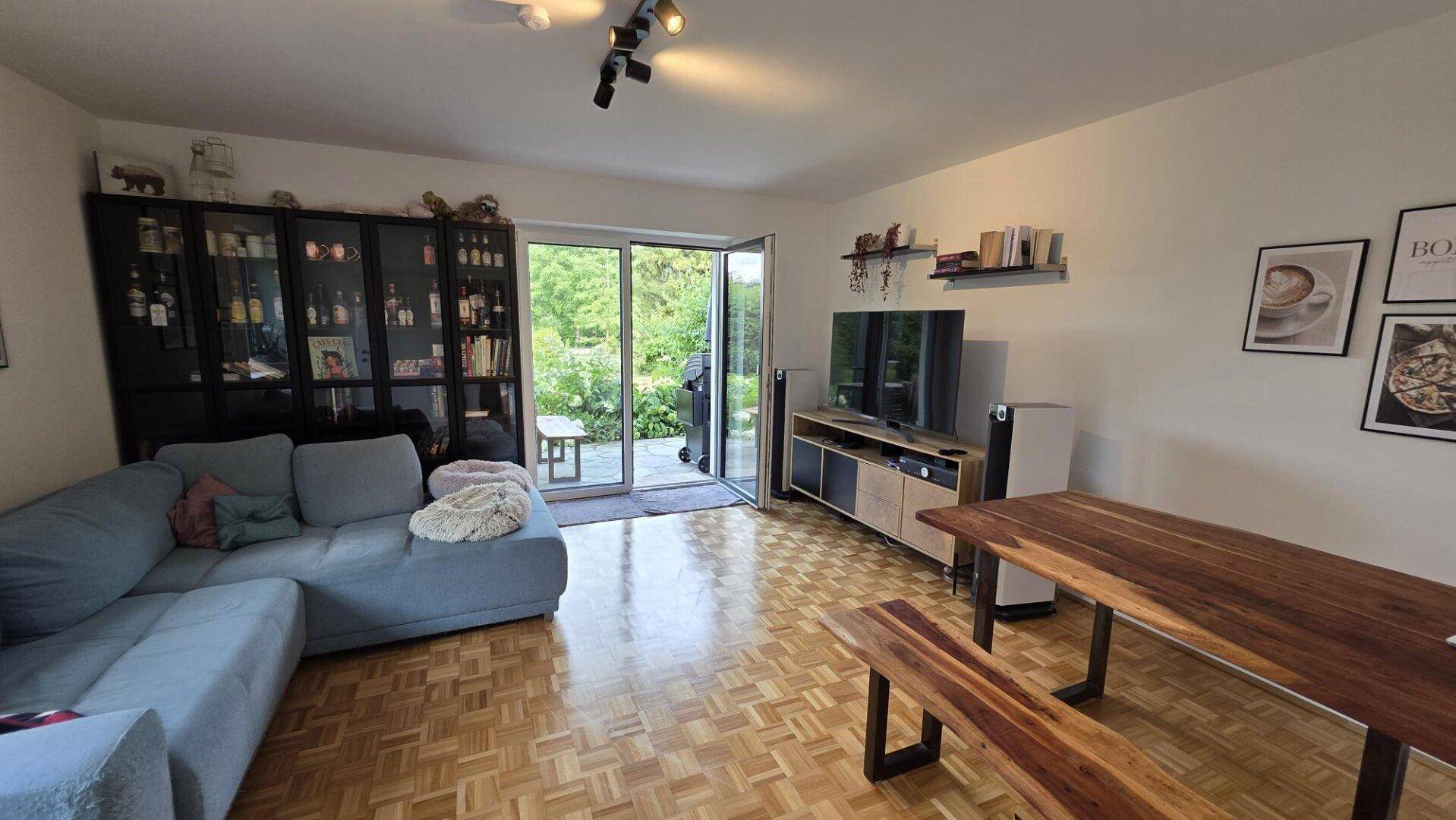 Gemütlicher Wohn-Essbereich mit Sofa, Holztisch und direktem Zugang zur Terrasse.
