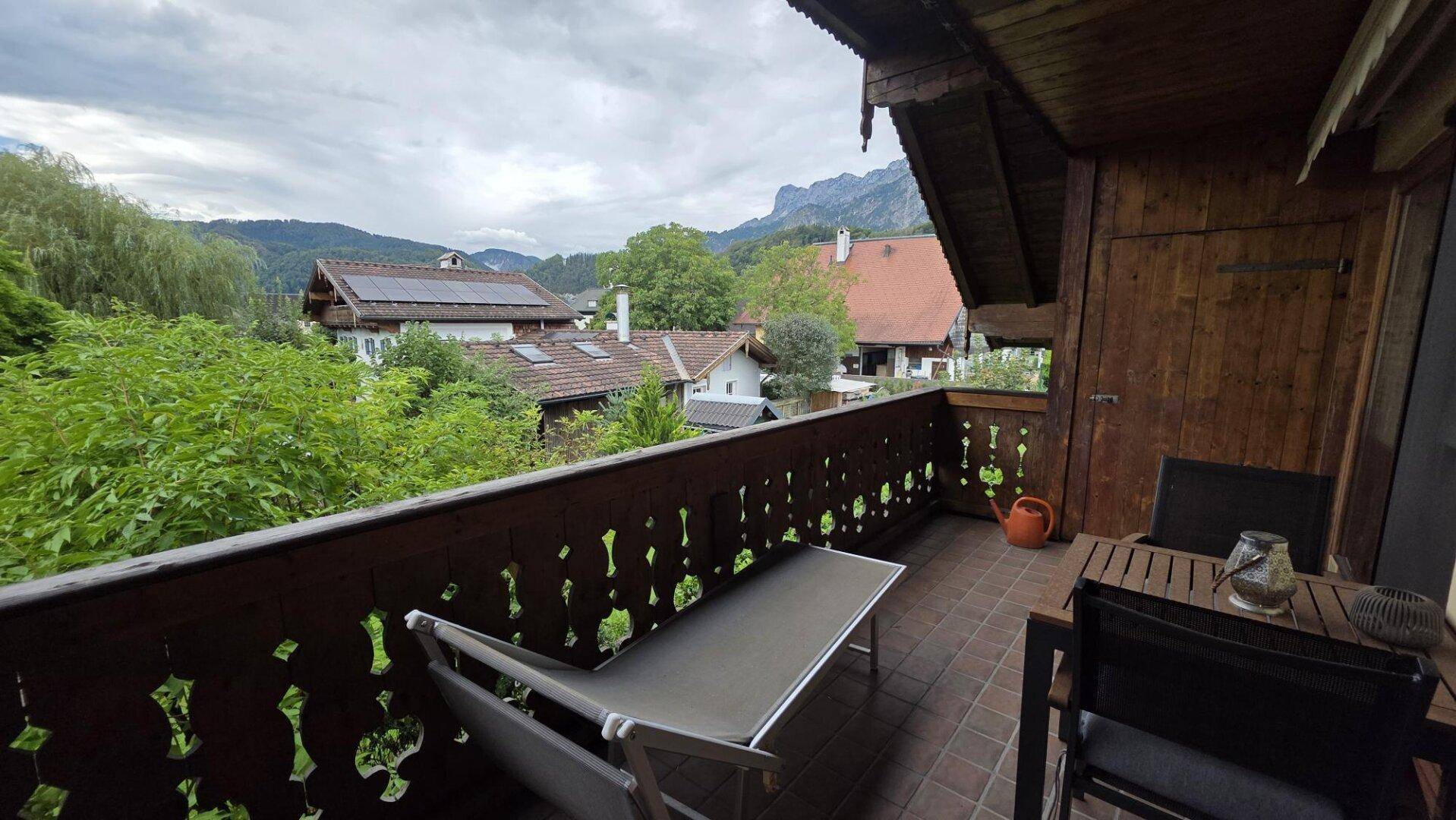 Traditioneller Holzbalkon mit Sitzgelegenheiten und einem malerischen Blick auf die Berge und Umgebung.