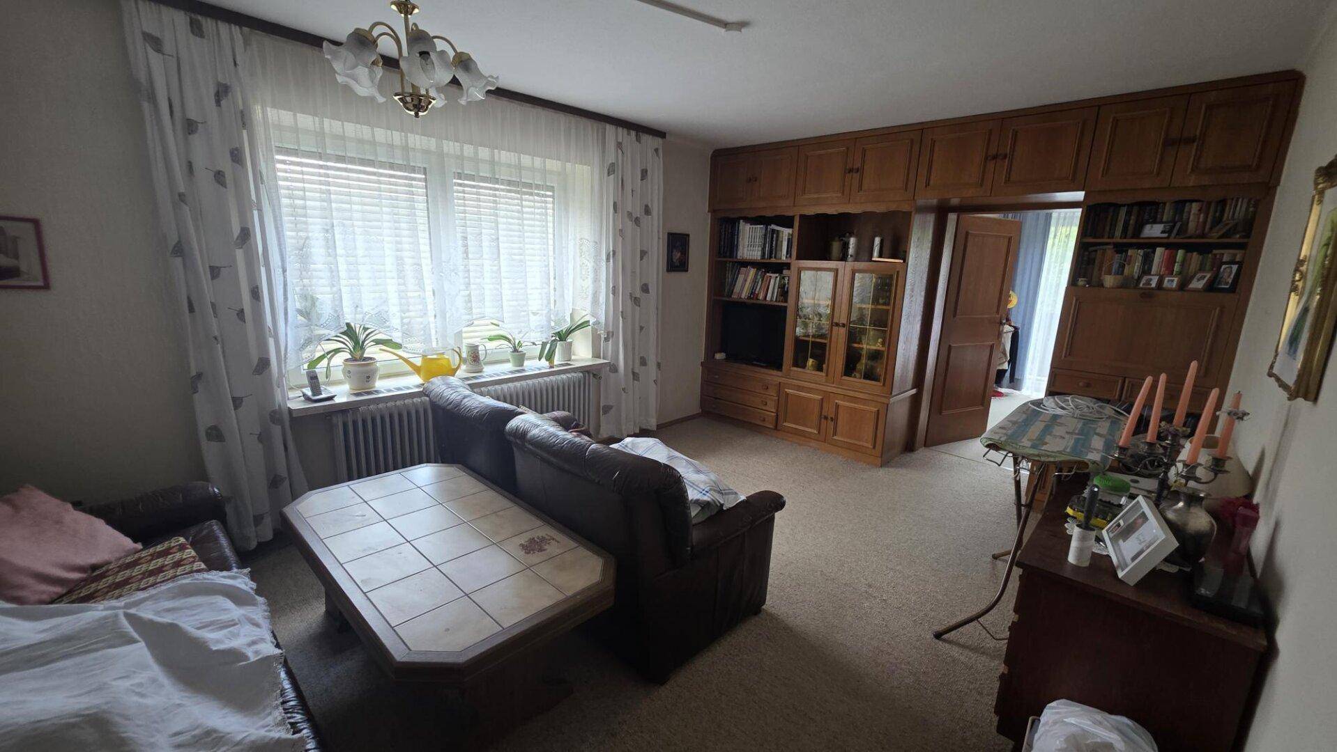 Gemütliches Wohnzimmer mit Sofa, Couchtisch und einer großen Holzschrankwand, die viel Stauraum bietet.