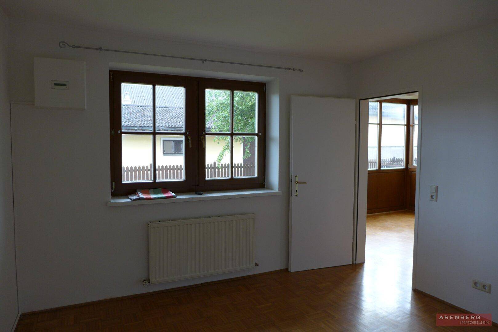 Leeres Zimmer mit Parkettboden, Fenster und Heizkörper, bereit zur individuellen Gestaltung.