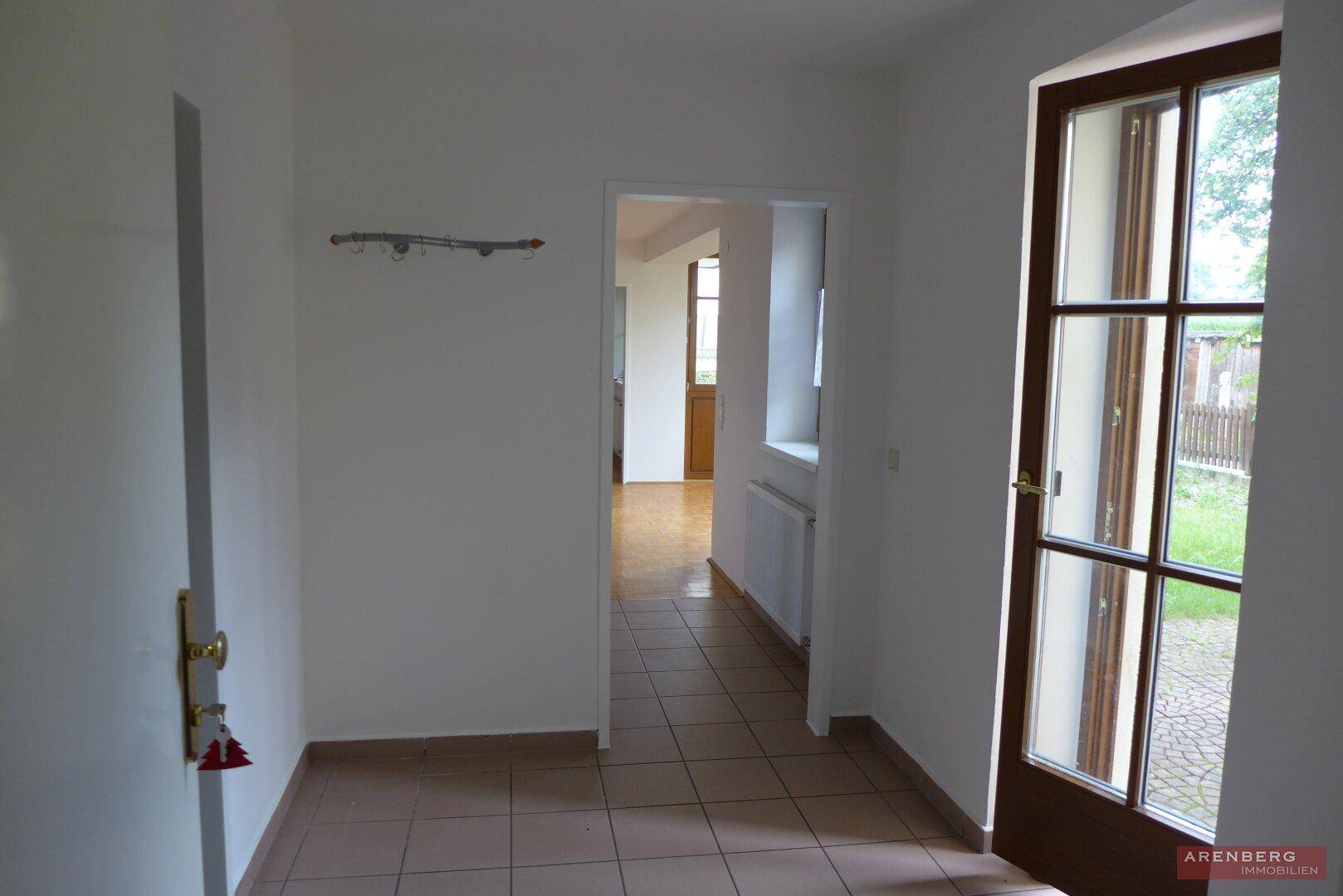 Heller Flur mit Fliesenboden und Zugang zu weiteren Räumen sowie zur Außentür.