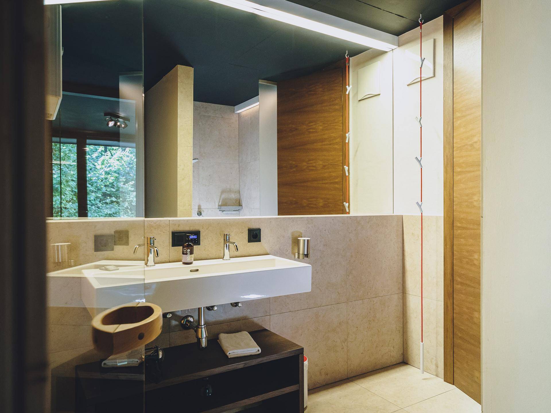 Modernes Badezimmer mit Doppelwaschbecken, großem Spiegel und hellen Fliesen, das eine ruhige Atmosphäre schafft.