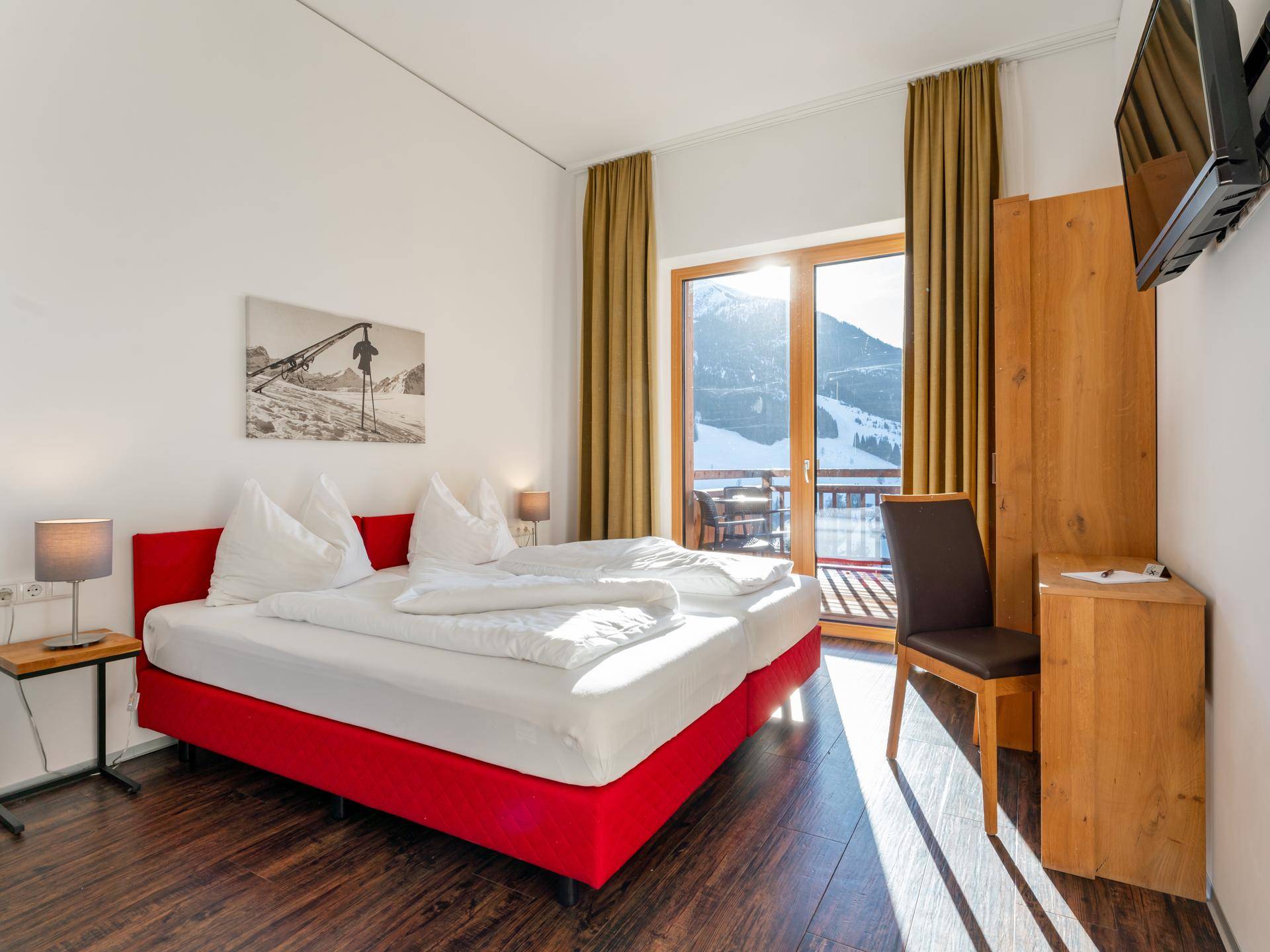 Gemütliches Schlafzimmer mit zwei Einzelbetten, Holzboden und Zugang zum Balkon mit Bergsicht.