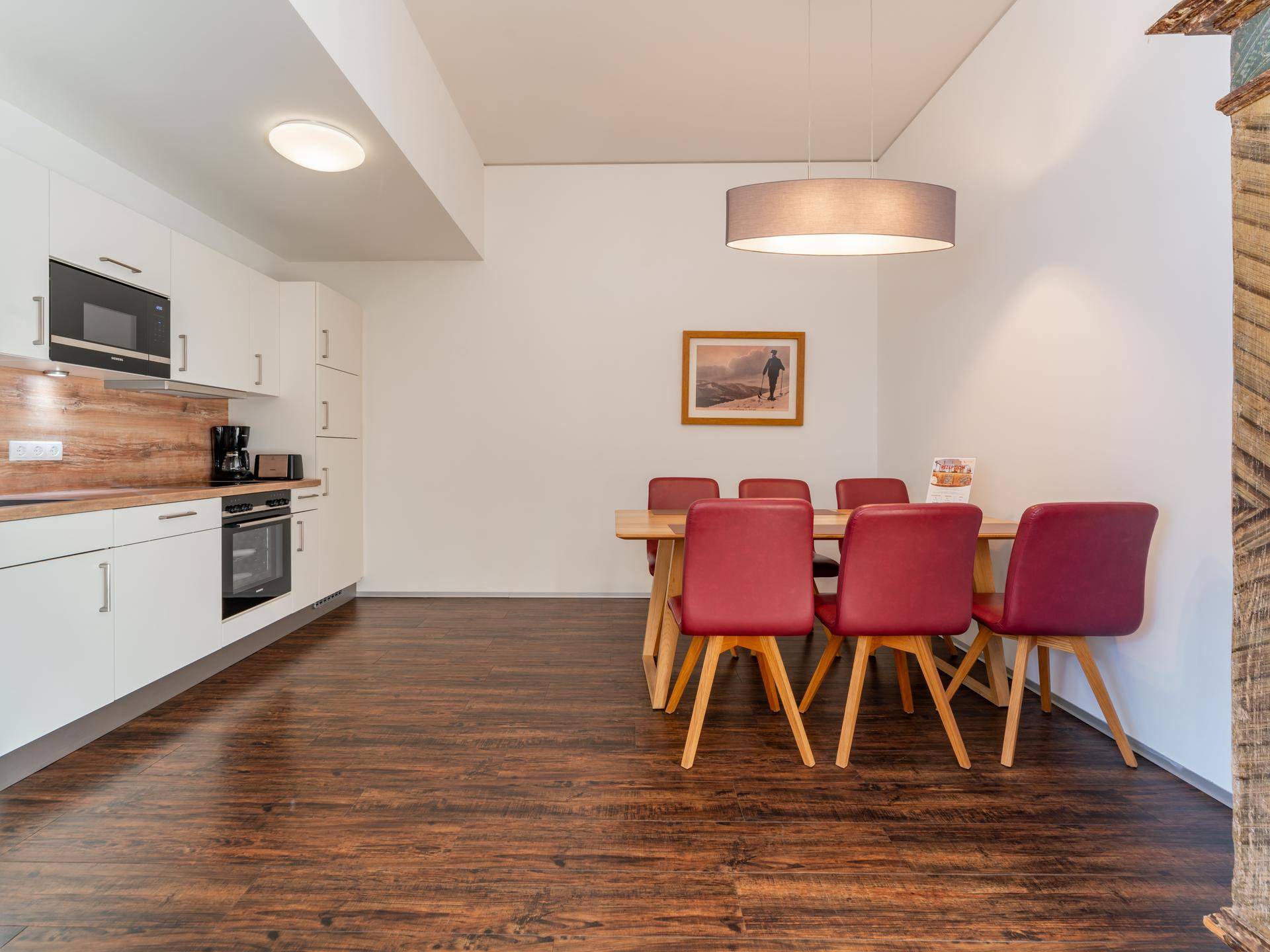 Moderne Einbauküche mit Holzarbeitsplatte und Essbereich mit roten Stühlen.
