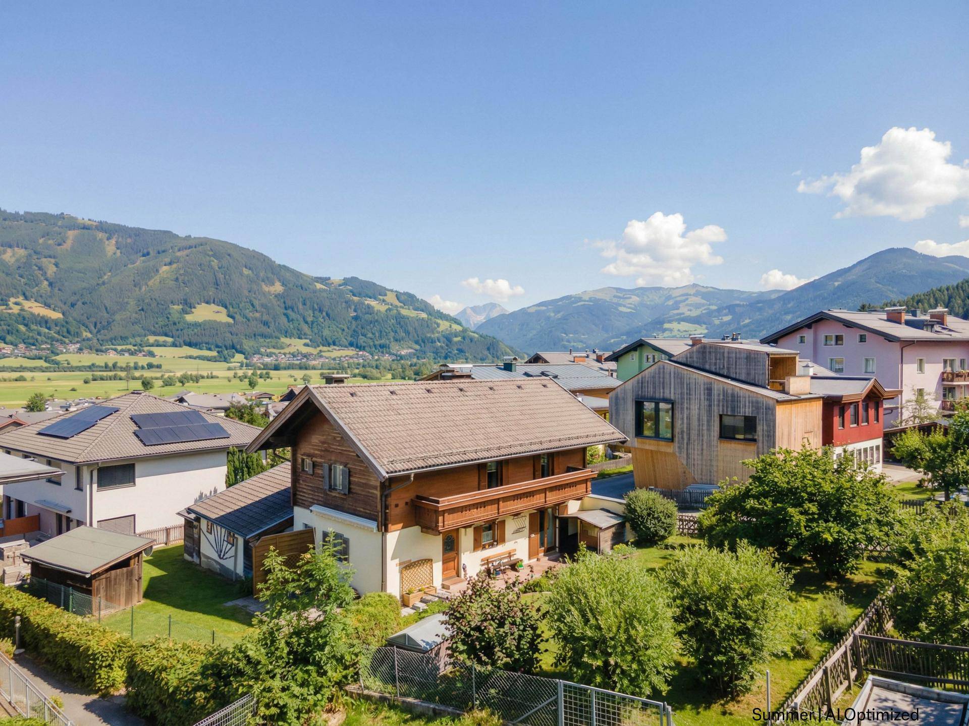 Panoramablick auf das Haus und die umliegende Siedlung mit weitreichender Aussicht auf die grüne Berglandschaft.