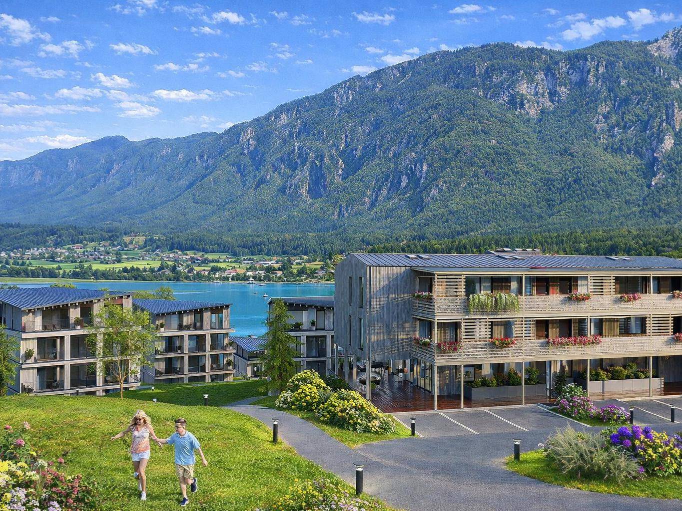 Moderne Wohngebäude am Seeufer mit Bergblick und gepflegten Grünflächen.