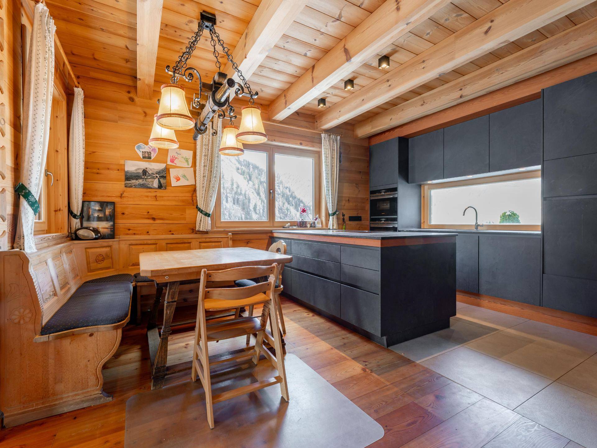 Moderne Küche mit dunklen Schränken und Kochinsel, kombiniert mit traditionellem Essbereich aus Holz.