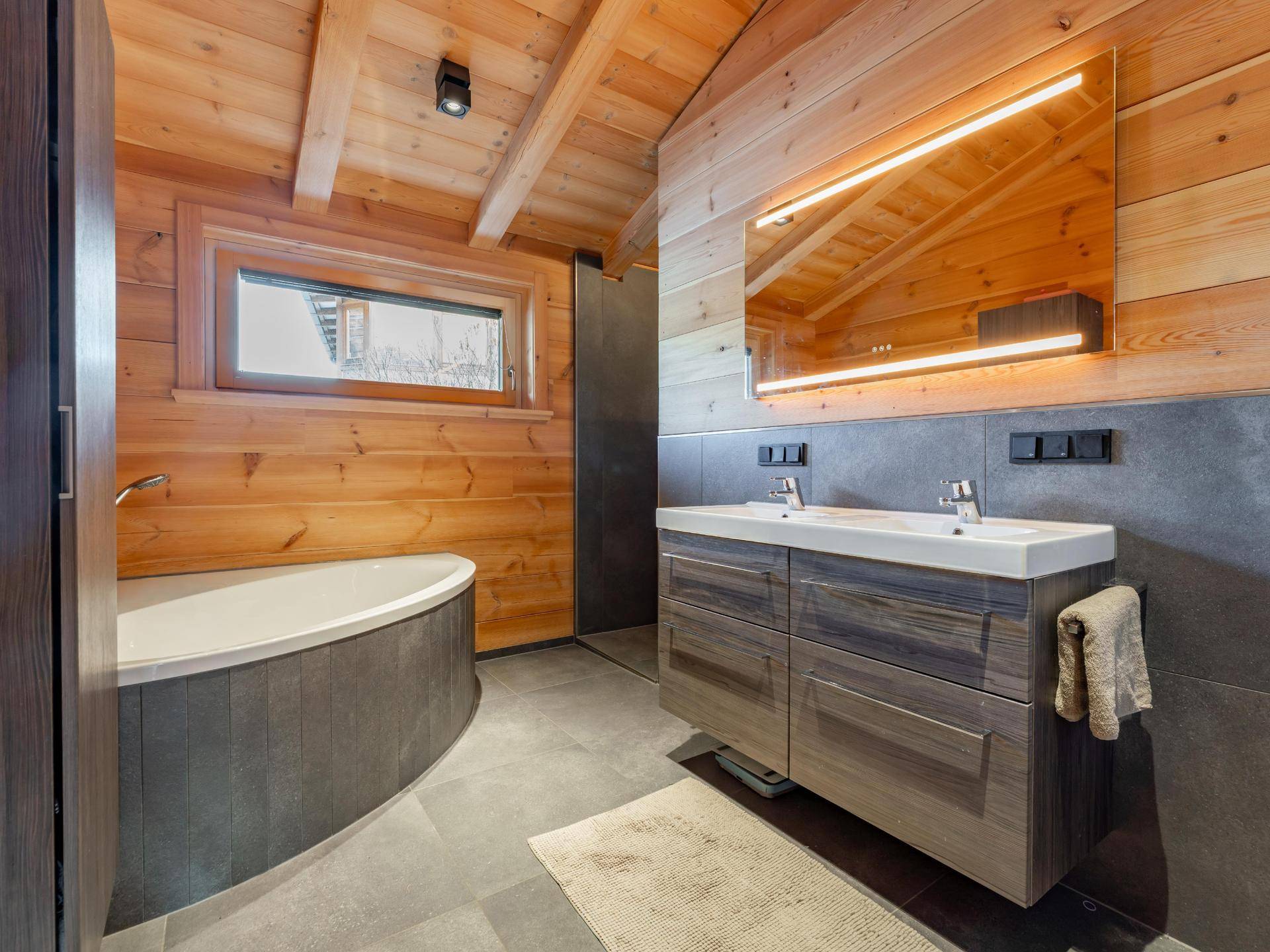 Modernes Badezimmer mit Holzakzenten, Doppelwaschbecken, Badewanne und separater Dusche.
