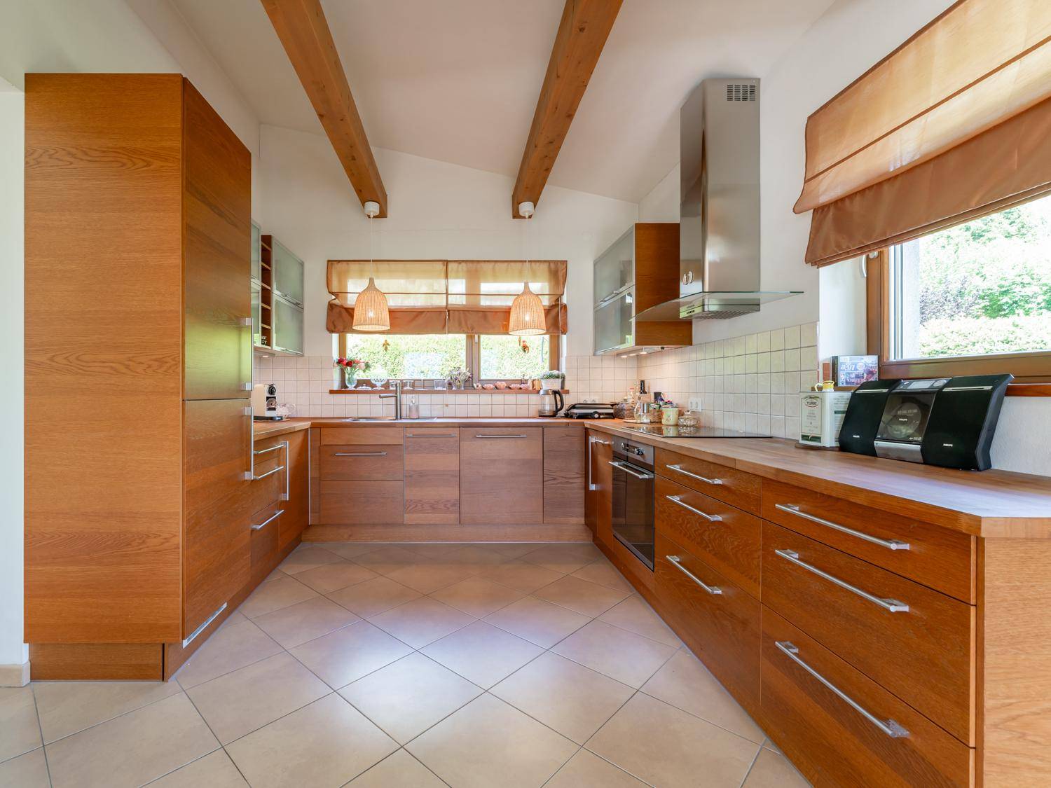 Gemütliche Küche mit Holzelementen, Fliesenboden und sichtbaren Deckenbalken.
