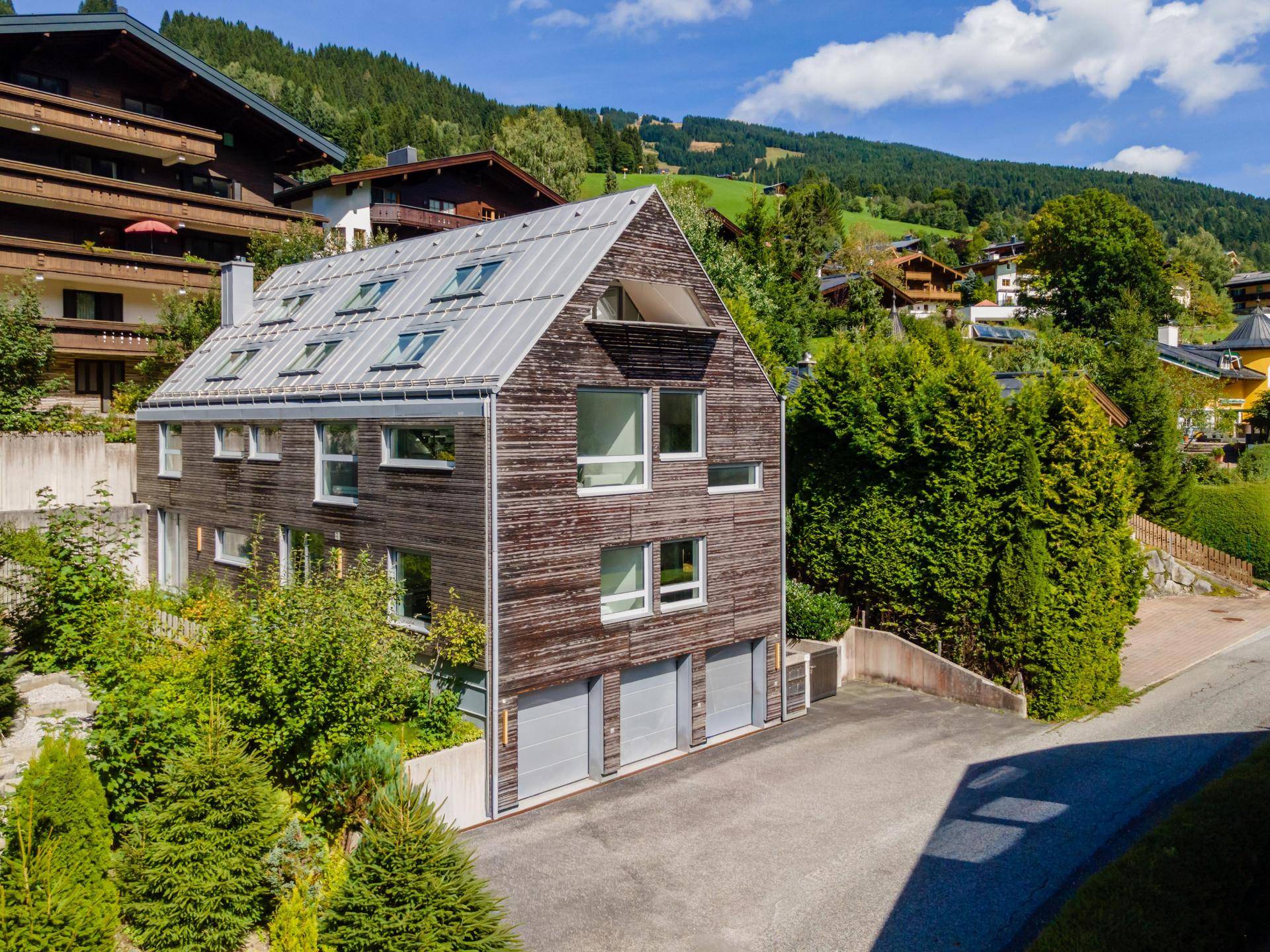Architektonisch ansprechendes Gebäude mit Holzfassade und Satteldach, eingebettet in eine alpine Landschaft.