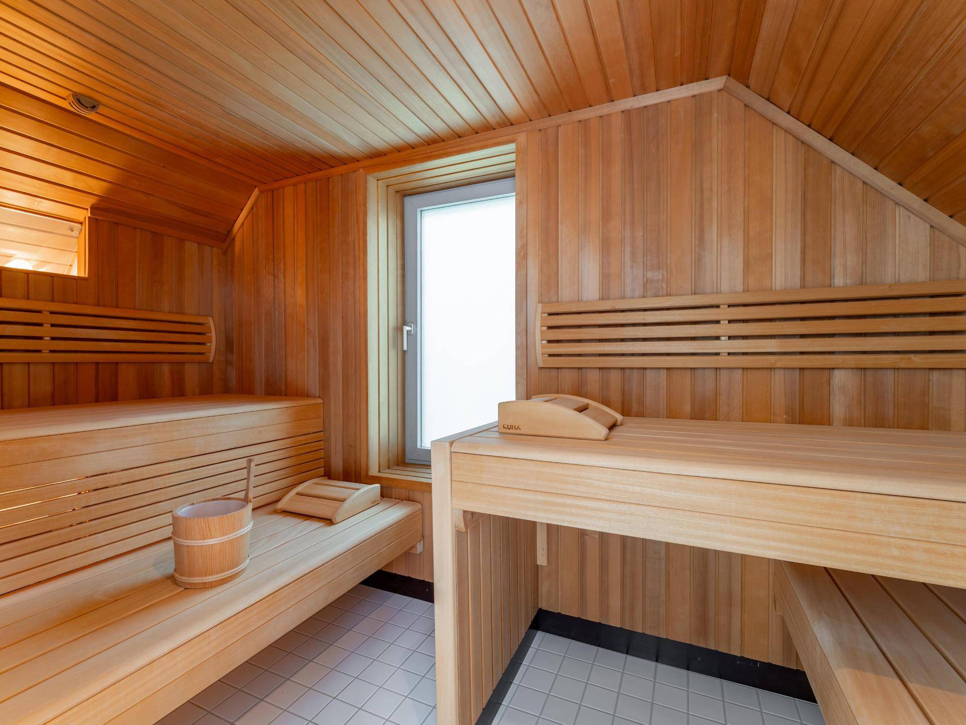 Gemütliche Holzsauna mit Sitzbänken und einem Fenster für natürliche Belüftung und Entspannung.