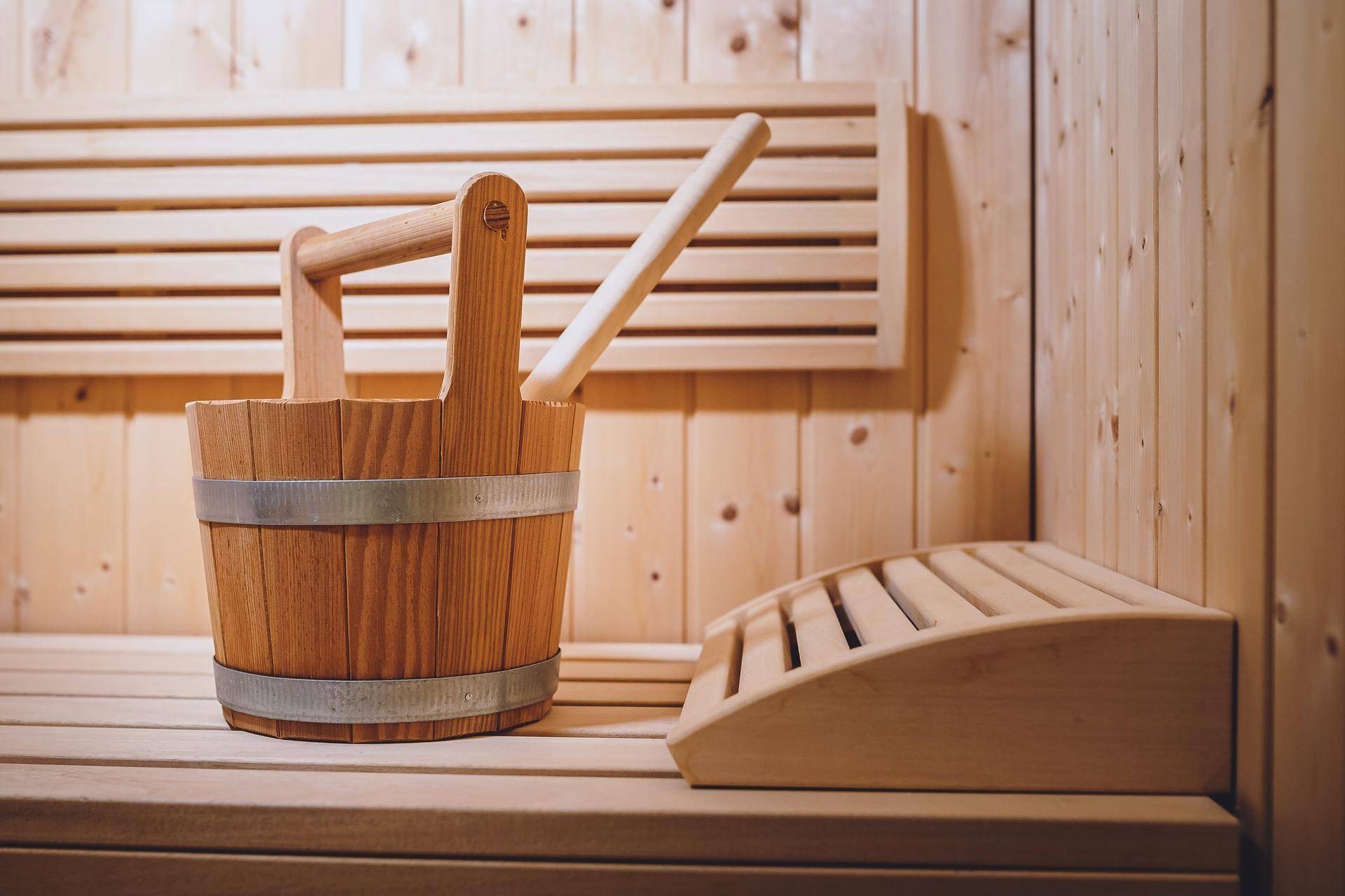 Detailansicht einer traditionellen Holzsauna mit Eimer und Schöpfkelle, bereit für entspannende Momente.