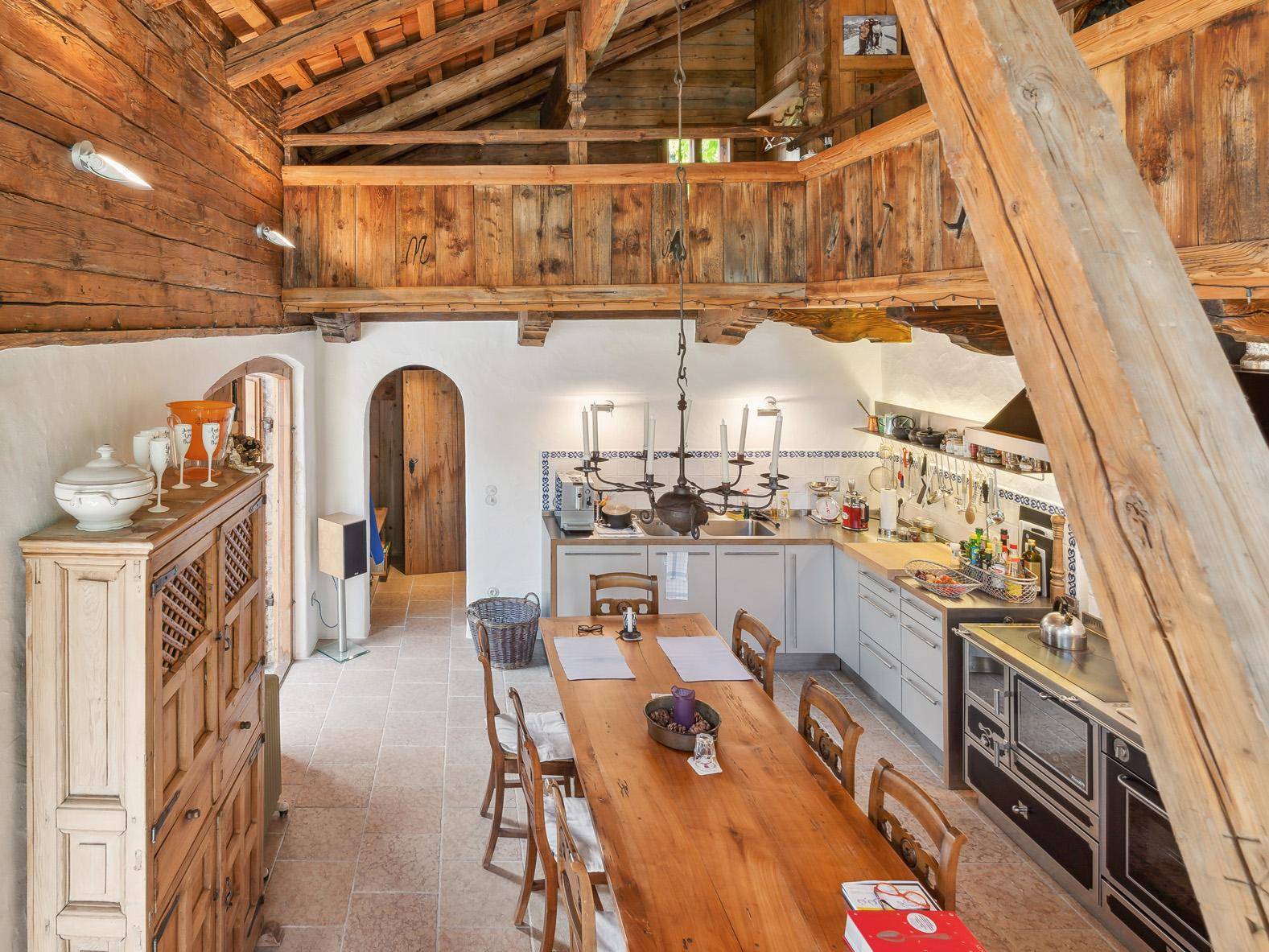 Geräumige Wohnküche mit hohen Holzdecken, freiliegenden Balken und rustikalem Essbereich mit Holztisch.