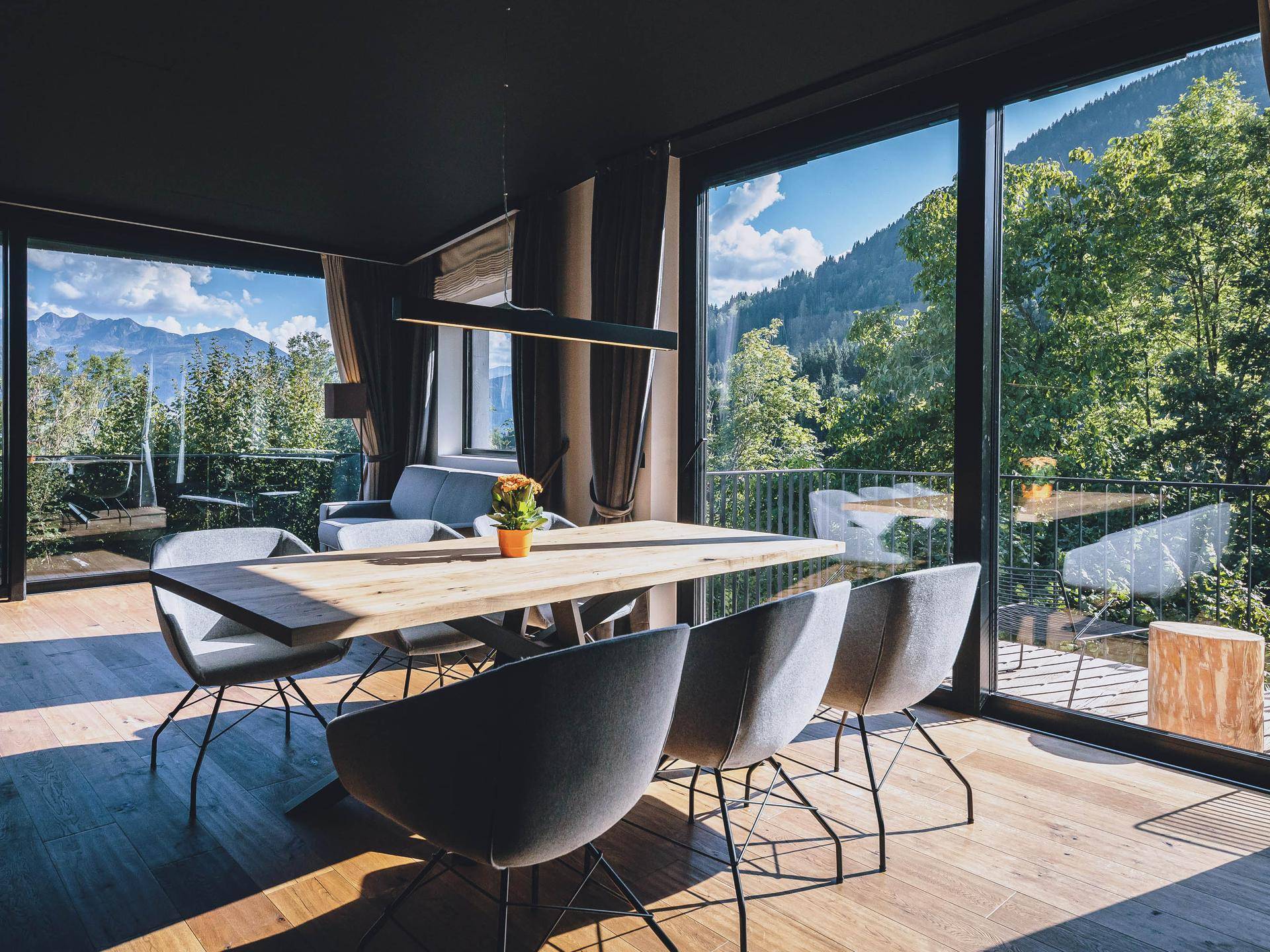 Heller Wohn-Essbereich mit Holzboden, großen Fenstern und Bergblick.