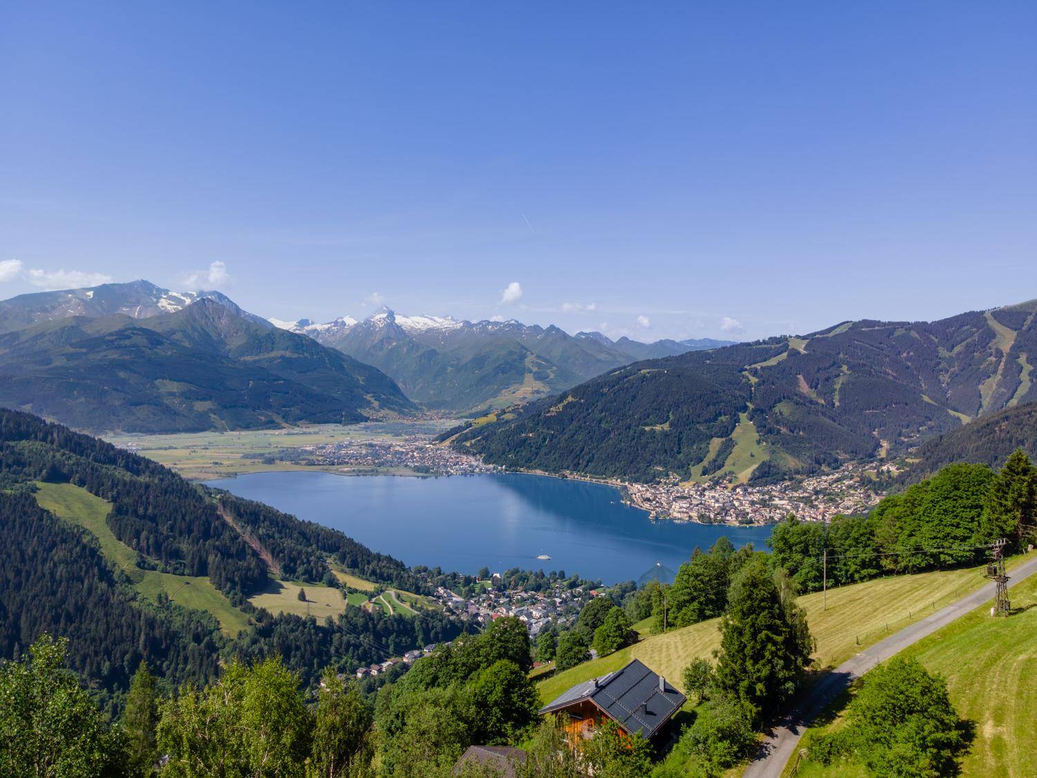 Panoramablick auf einen großen See, umgeben von majestätischen Bergen und einer malerischen Stadt.