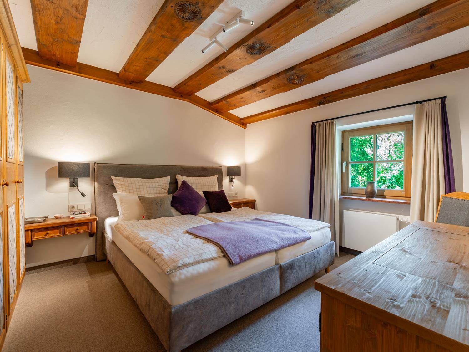 Gemütliches Schlafzimmer mit Holzbalkendecke, großem Bett und traditionellem Holzschrank.