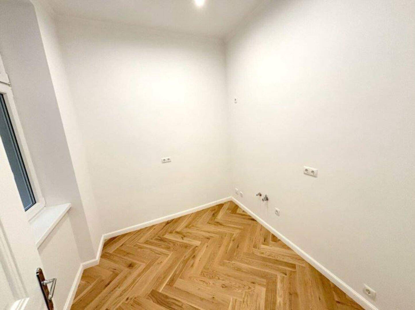 Kleiner Raum mit Fischgrätparkett und Fenster, ideal als Abstell- oder Hauswirtschaftsraum.