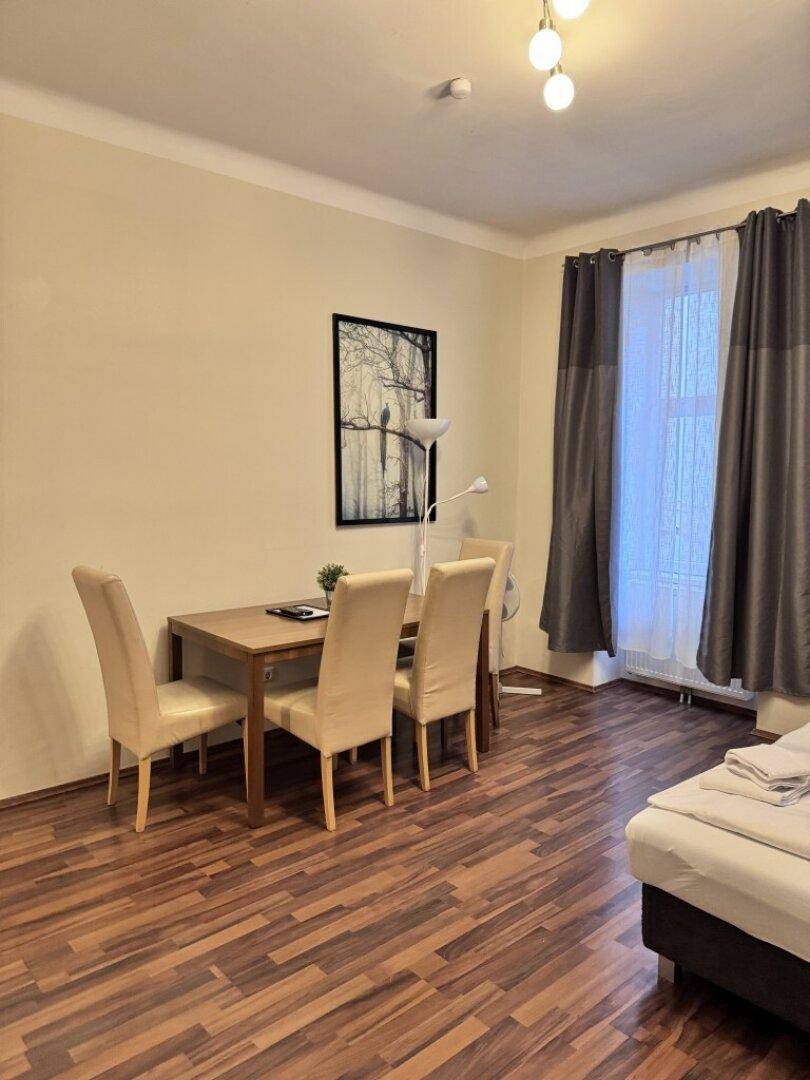 Heller Wohn- und Essbereich mit Holztisch, beigen Stühlen und großem Fenster.