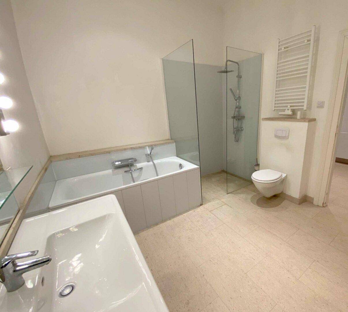 Helles Badezimmer mit Badewanne, begehbarer Dusche und beheiztem Handtuchhalter.