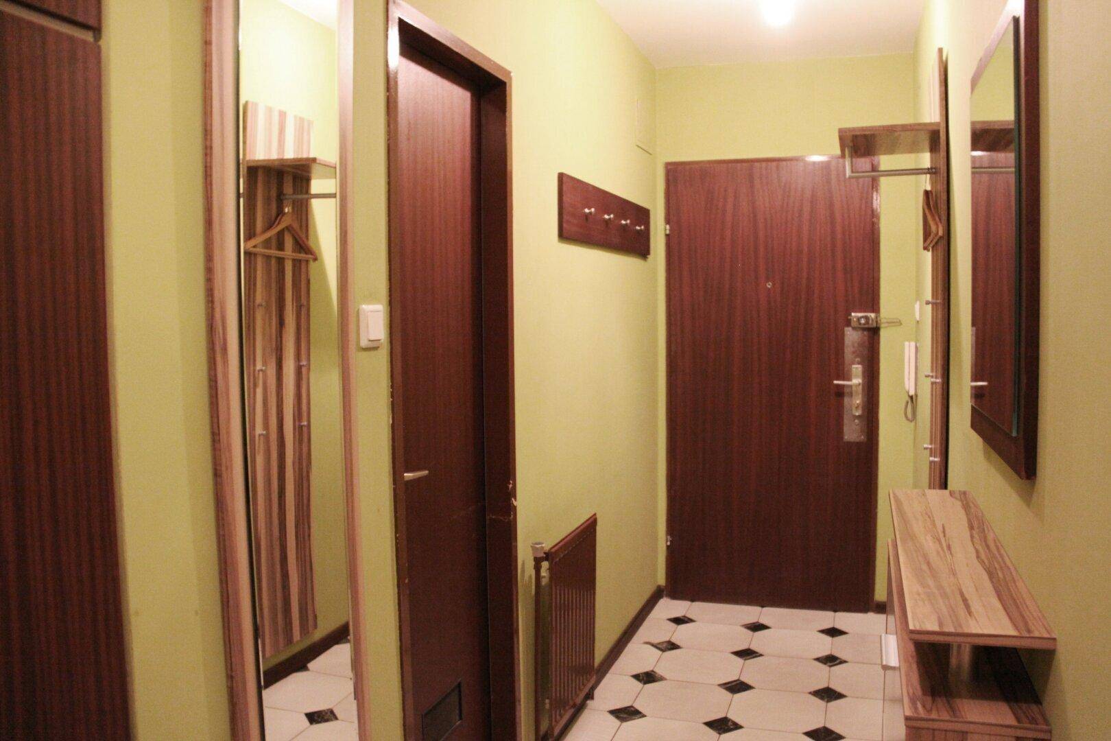 Eingangsbereich mit gefliestem Boden, Garderobe und Spiegeln an den Wänden.