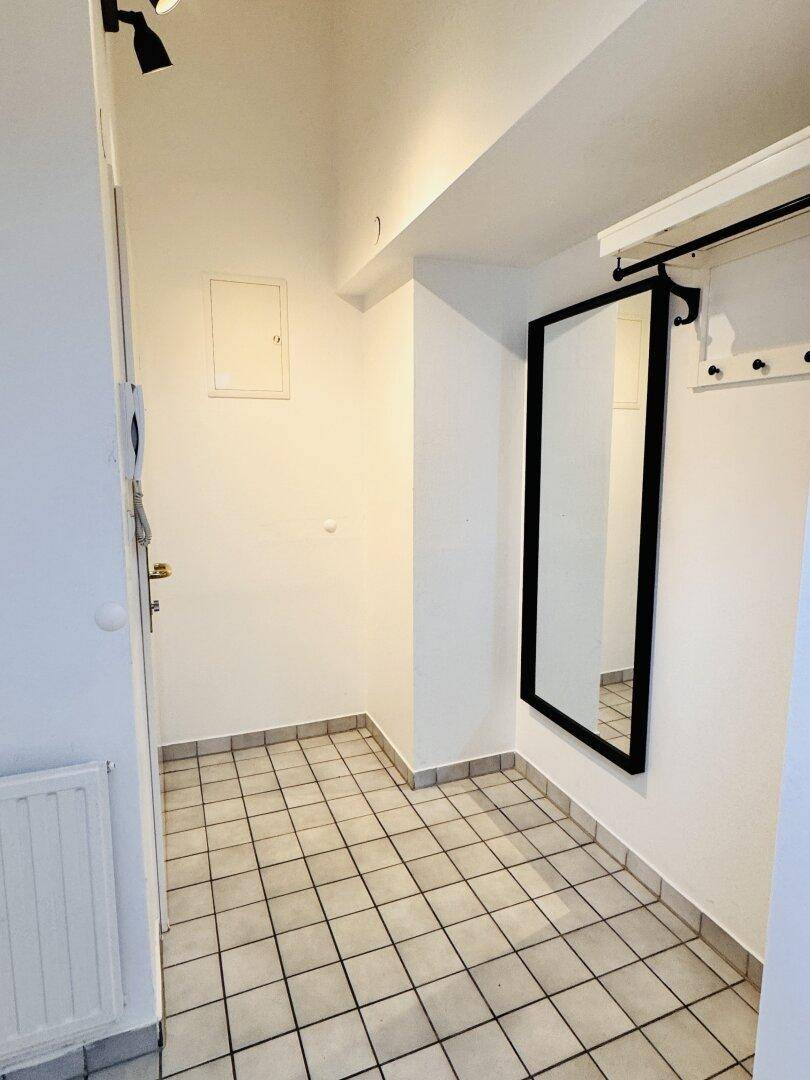 Funktionaler Flur mit Fliesenboden, Wandspiegel und einer schlichten Garderobenablage.