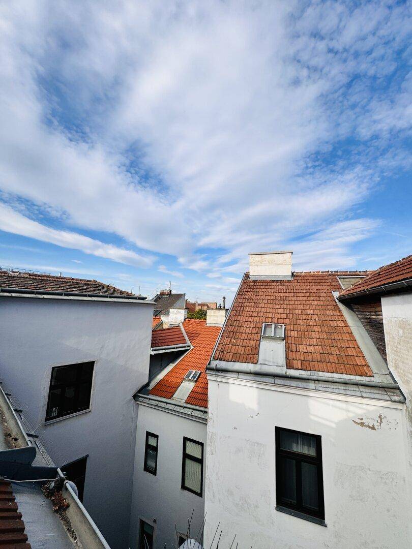 Panoramablick über die umliegenden Dächer mit roten Ziegeln unter einem weiten blauen Himmel.